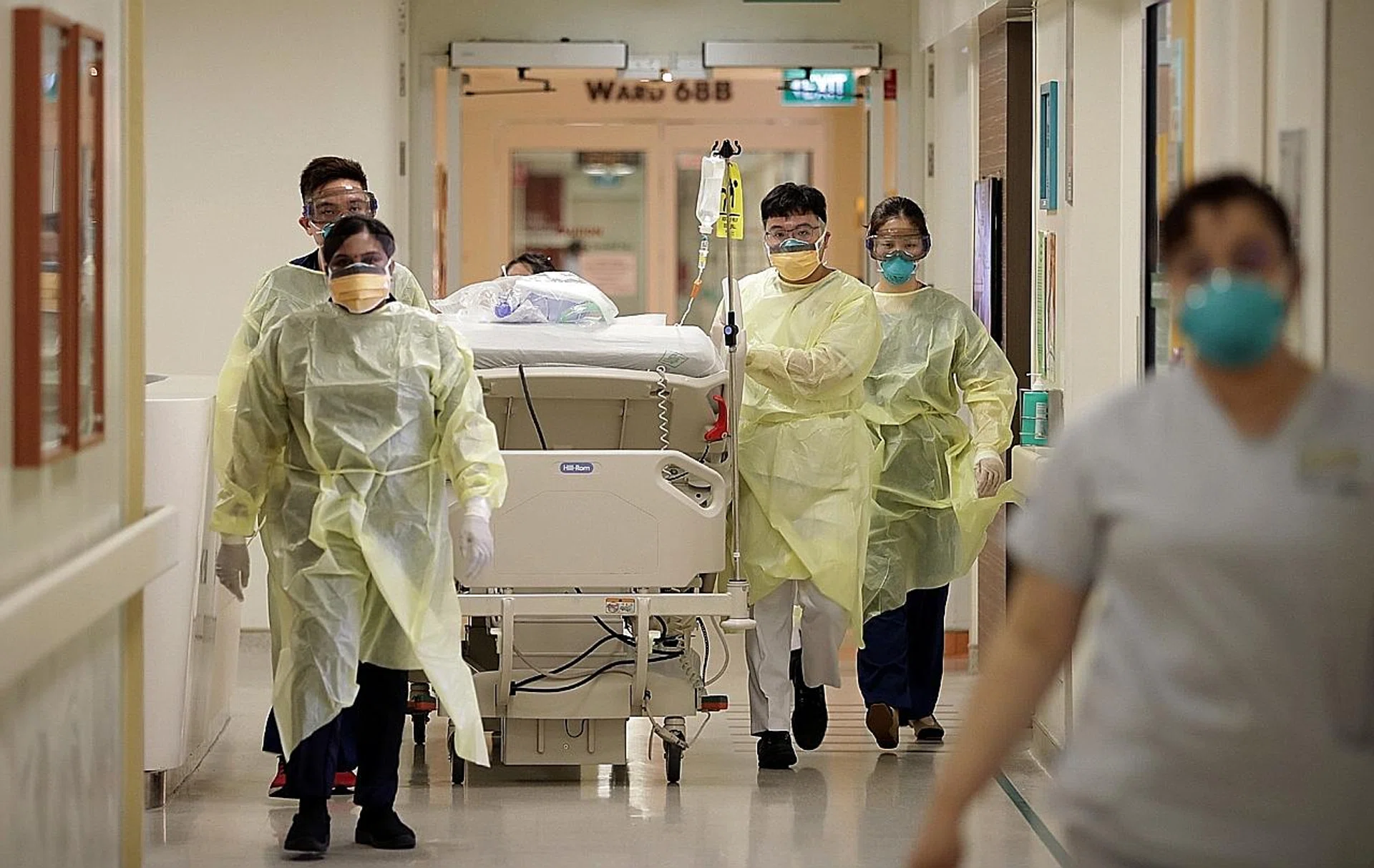 Healthcare workers in the Singapore General Hospital isolation ward assist in the transfer of a suspected Covid-19 patient to an isolation room. 
