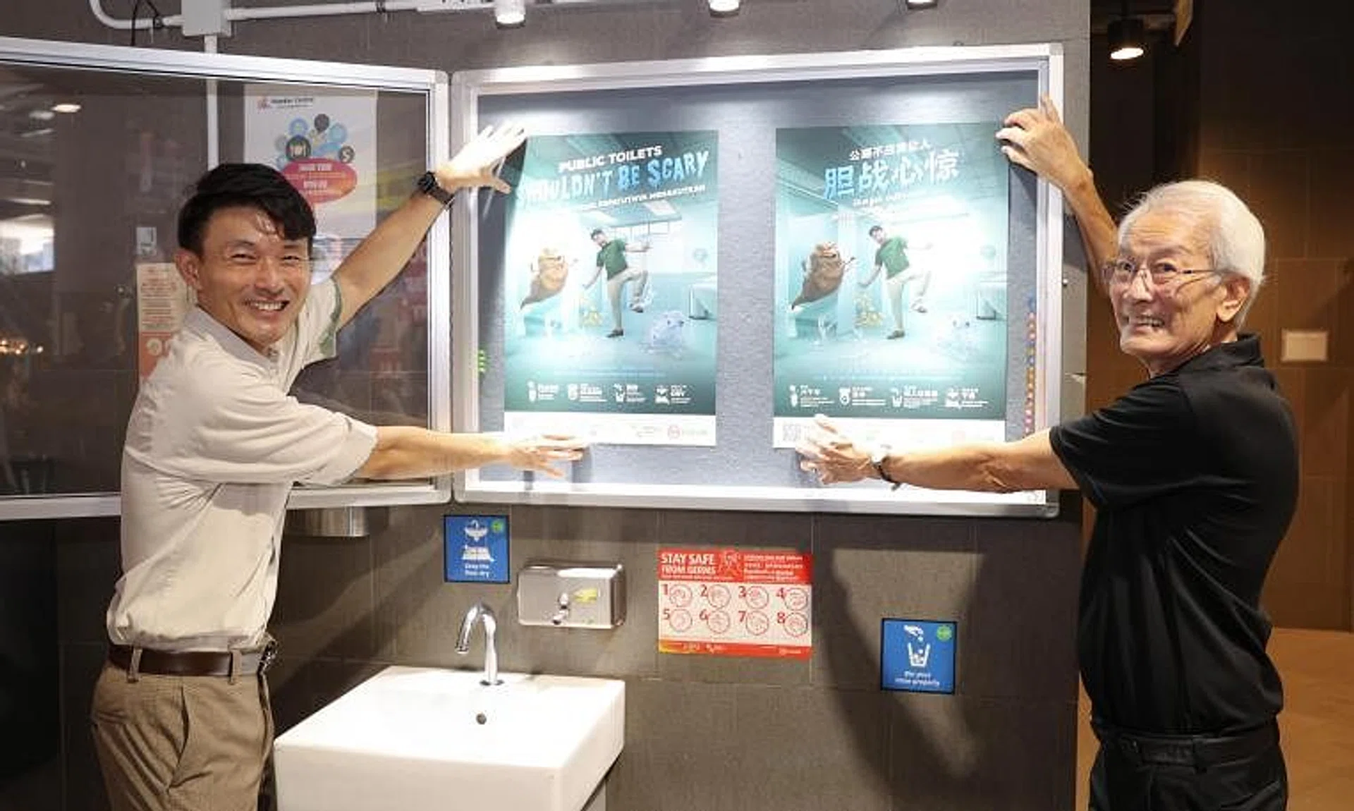 Senior Parliamentary Secretary for Sustainability and the Environment Baey Yam Keng (left) and Chairman of the Public Hygiene Council Edward D’Silva putting up posters for this year’s clean public toilets campaign.