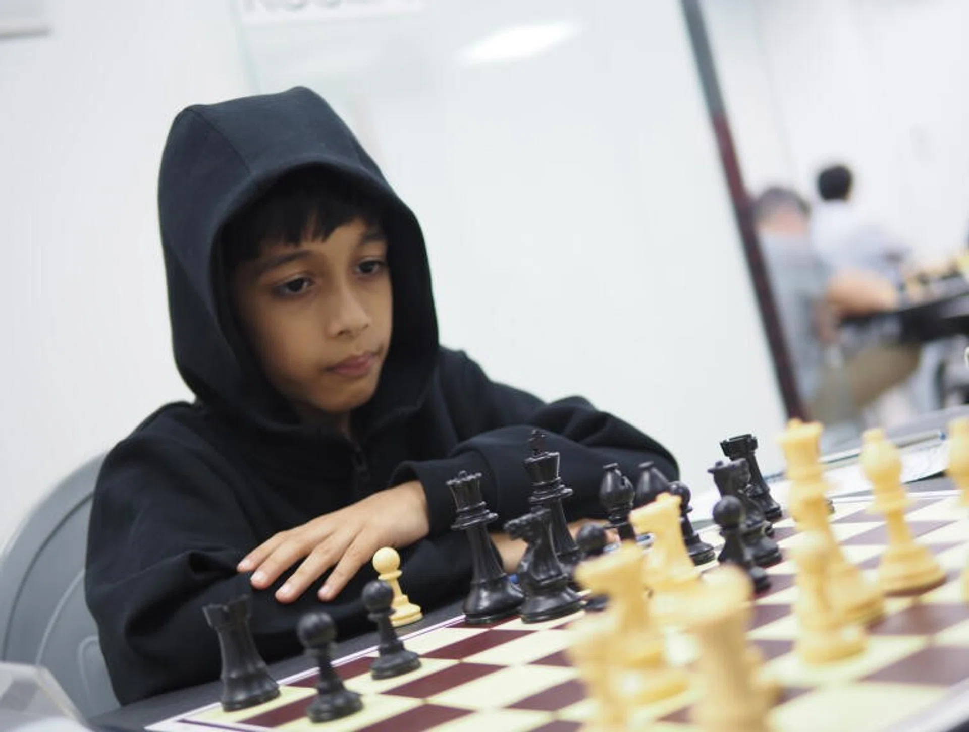 Ashwath Kaushik, 7, has to use a booster cushion to reach the chess board when he was competing in the 2023 Singapore National Chess Championships.