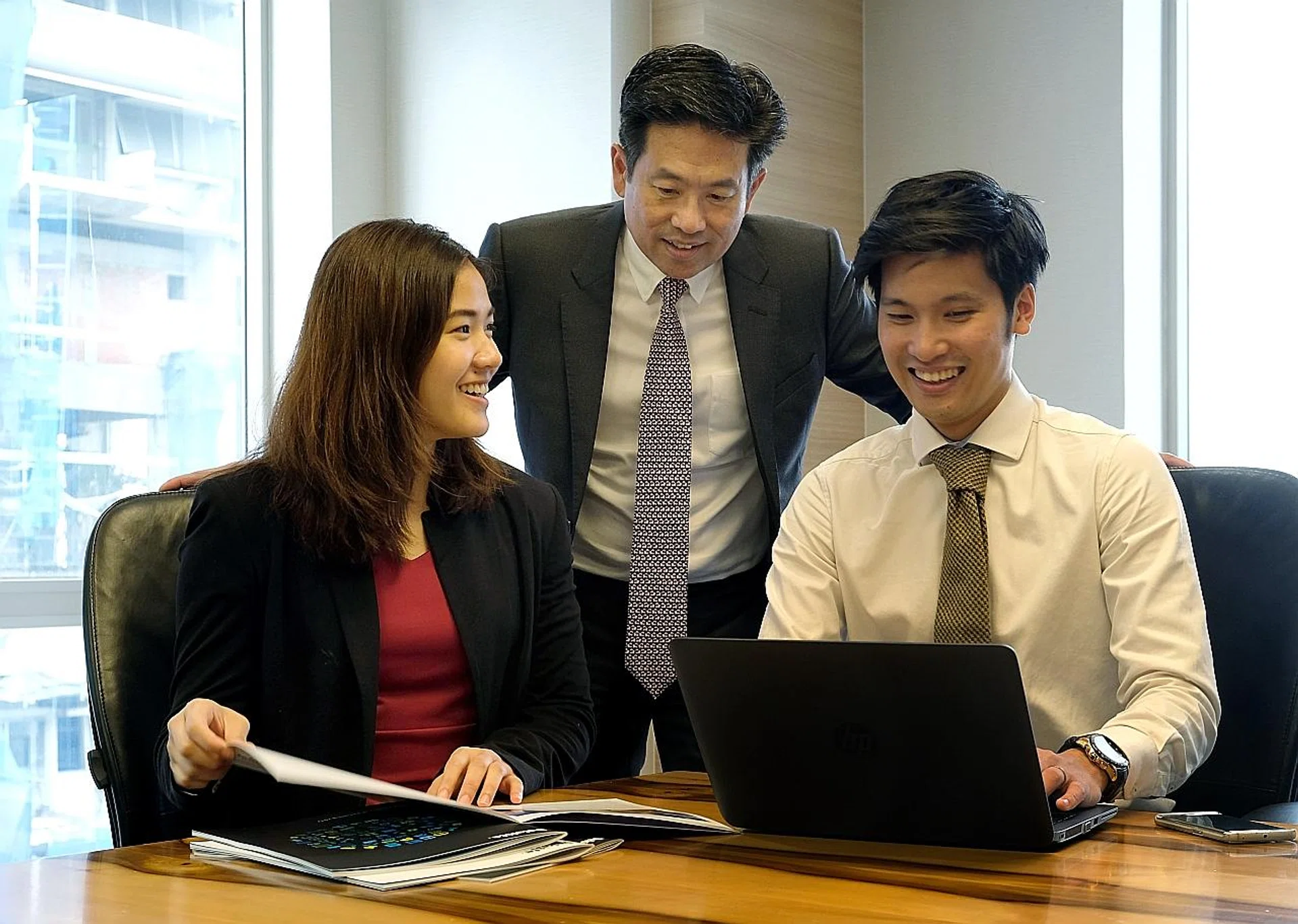 Deloitte Southeast Asia and Singapore CEO Philip Yuen (centre) speaking with his staff, national netballer Kimberly Lim and former national shuttler Derek Wong at the office. Deloitte is a big supporter of Singapore sports. 