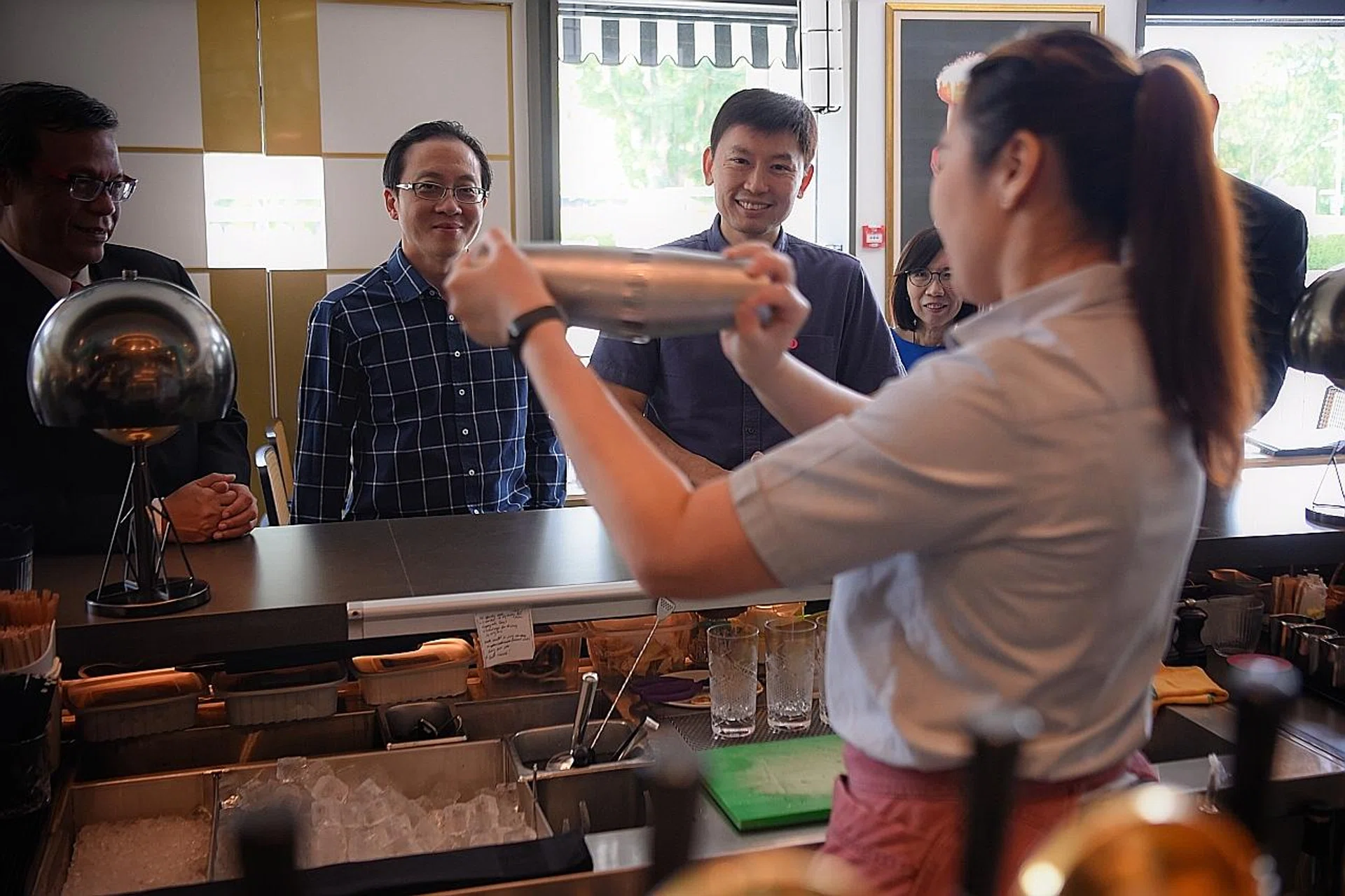 Mr Chee Hong Tat (centre), Senior Minister of State for Trade and Industry as well as Education, observing Fairmont Singapore hotel employee Isabella Lim concoct a cocktail at Prego restaurant yesterday. 