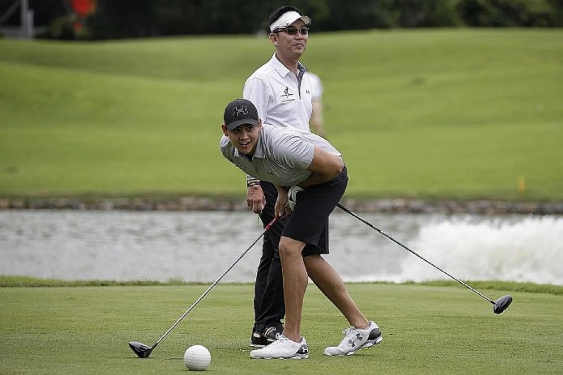 DIFFERENT STROKES: Joseph Schooling looking at his tee shot as SMRT general manager Kwek Hyen Chee waits for his turn at the Singapore Swimming Association golf fundraiser at Tanah Merah's Garden Course yesterday.  
