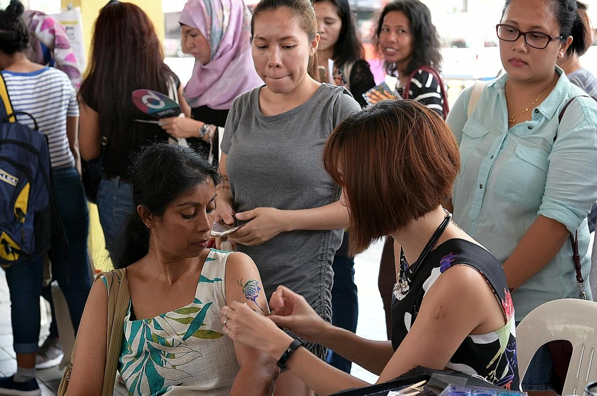 Sri Lankan domestic worker, Ms S.V. Dewanarayana, getting a free 'tattoo' at the Mayday Domestic Workers Celebration at Hougang bus interchange. 