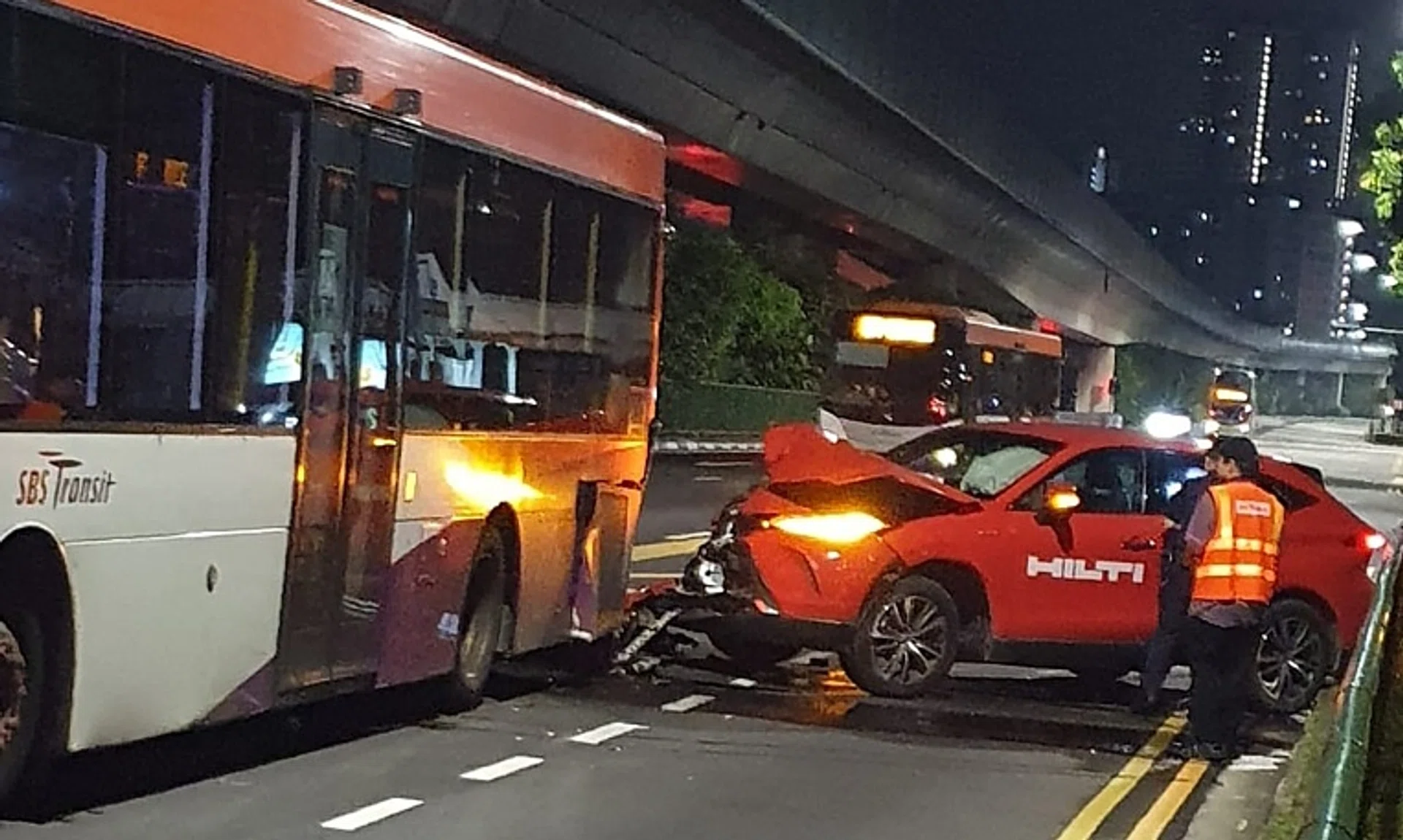 Photos of the accident show a red car with a damaged hood behind a bus with a bumper that fell on the road.