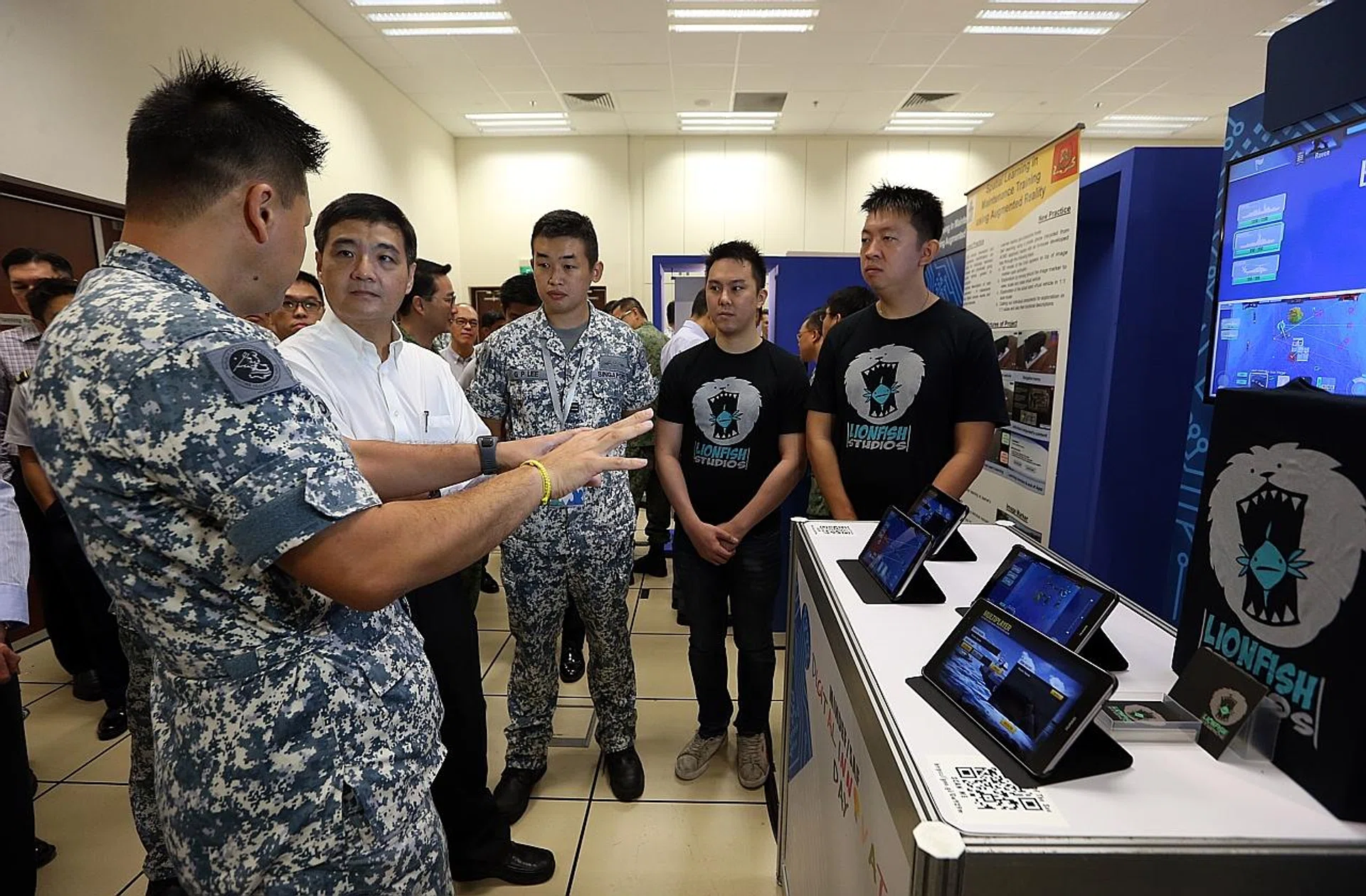 Senior Minister of State for Defence Heng Chee How (in white) at Changi Naval Base being briefed on how gaming technology can be used for training .
