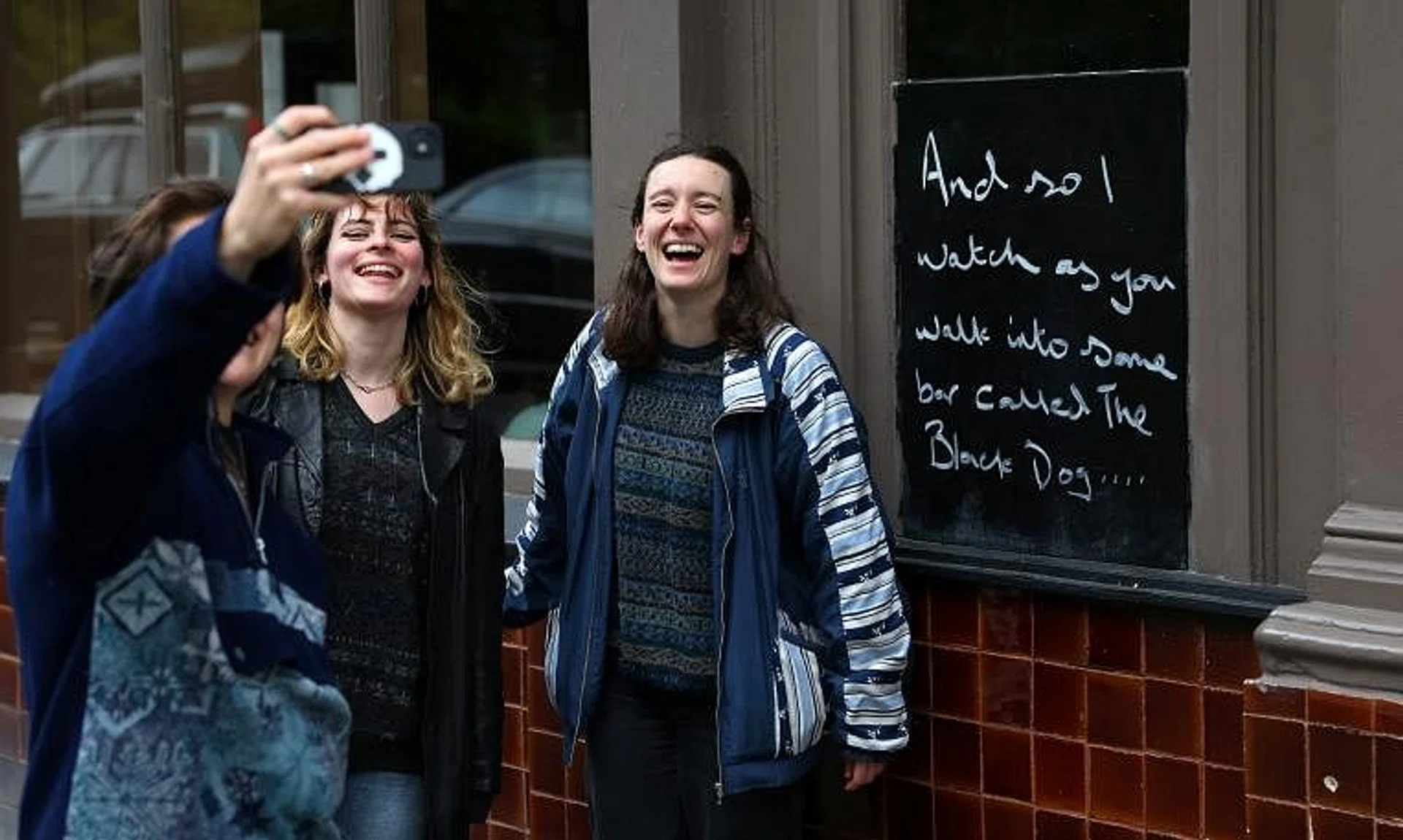 Fans of Taylor Swift take images next to lyrics from the song The Black Dog by Taylor Swift, written outside The Black Dog pub.