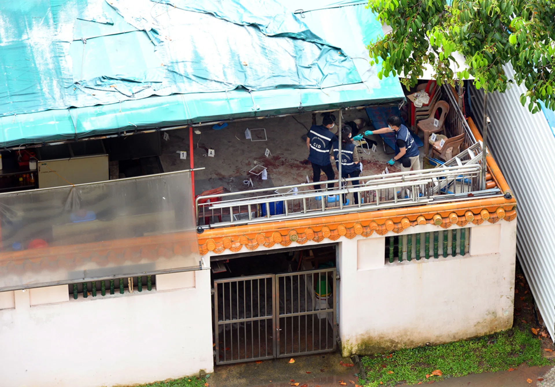 Police at the scene where former temple medium Tan Poh Huat, 53, was found lying motionless in a pool of blood outside the prayer hall of Chua Chu Kang Lian Sing Keng temple on Teck Whye Lane.