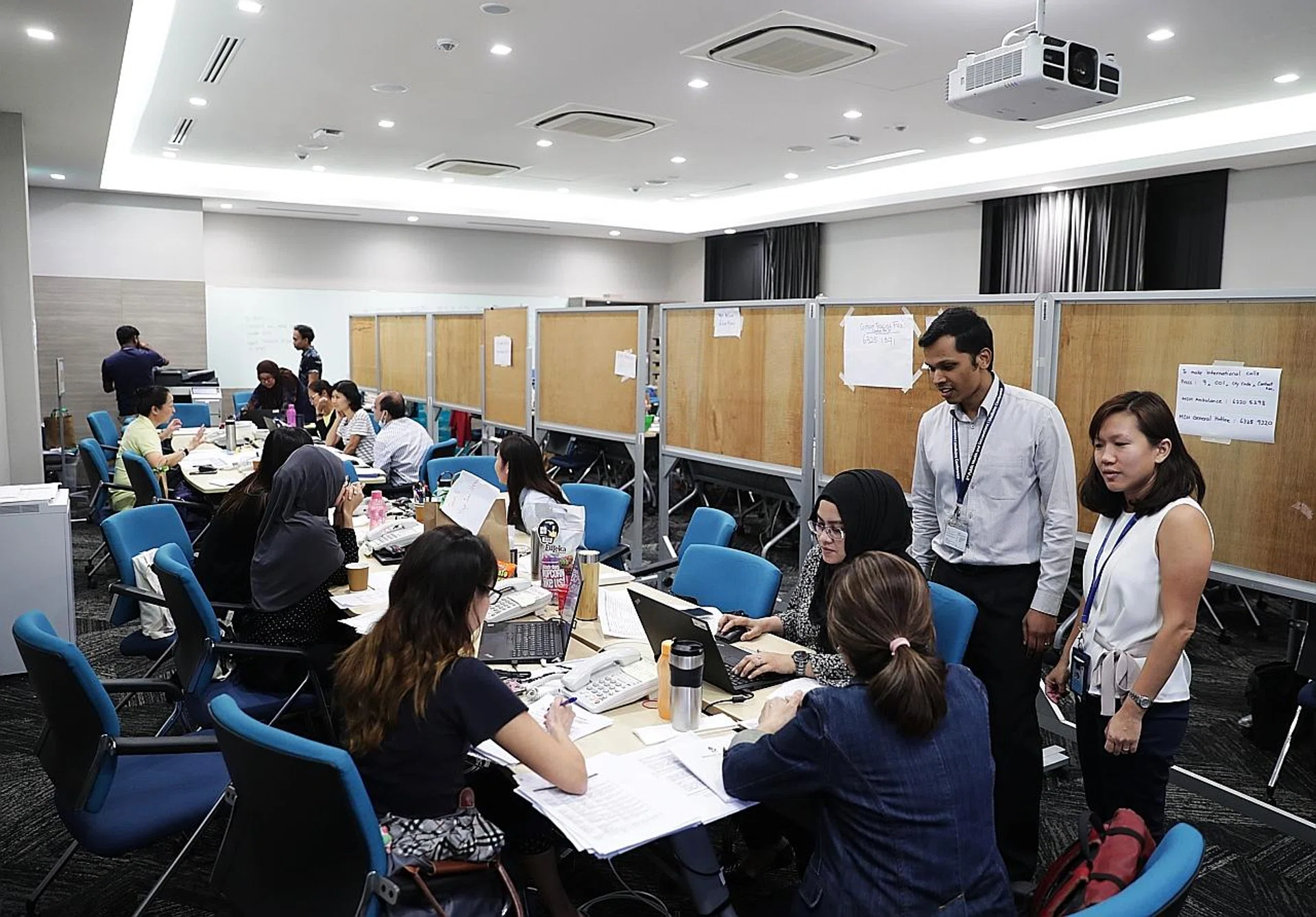 Assistant directors from the Health Ministry's Communicable Diseases Division Olivia Oh and Pream Raj (standing) with officers carrying out contact tracing on confirmed coronavirus patients. 