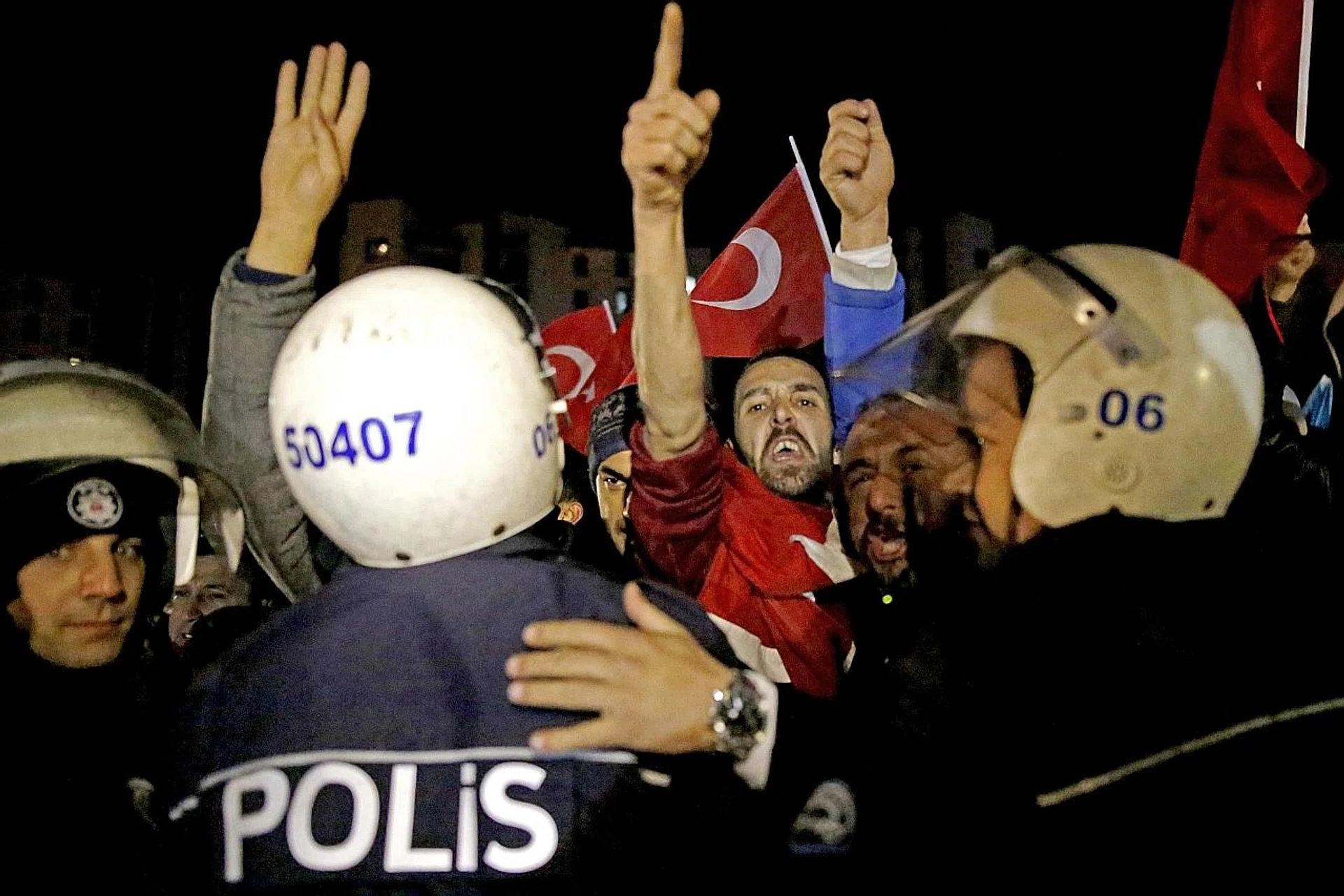 Supporters of Mr Erdogan shout slogans against the Netherlands and hold Turkish flags in front of the Dutch Embassy in Ankara. 