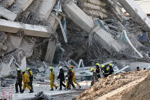 Rescue personnel walk near a building that collapsed on March 28.