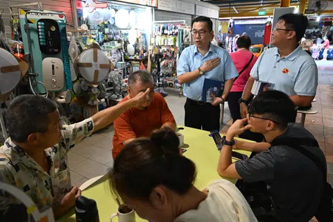 WP East Coast candidate Jasper Kuan (left, standing) greeting residents during a walkabout at Bedok 85 Fengshan Hawker Centre on April 25.