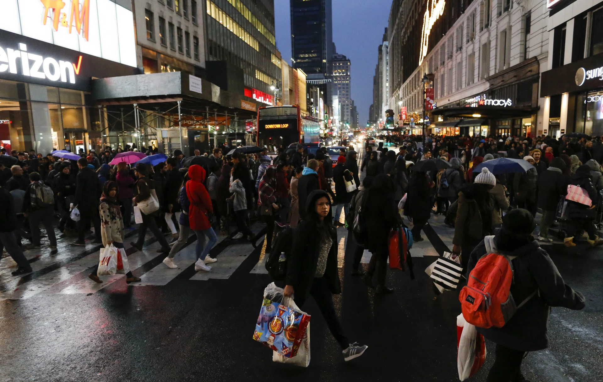 Shoppers cross the street carrying retail bags during Black Friday events 