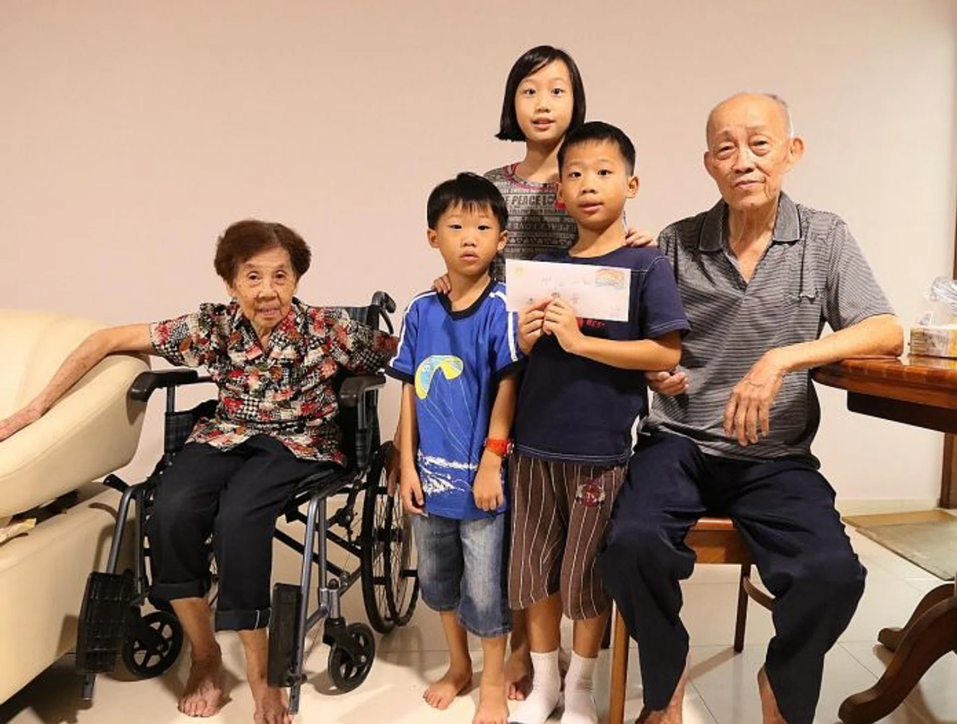 LITTLE ONES, BIG HEARTS: Siblings Trinity Ong, 10, Noah, 8, and Caspar, 5, with Mr Neo Chwee Eng and his wife, and the envelope containing the donation.