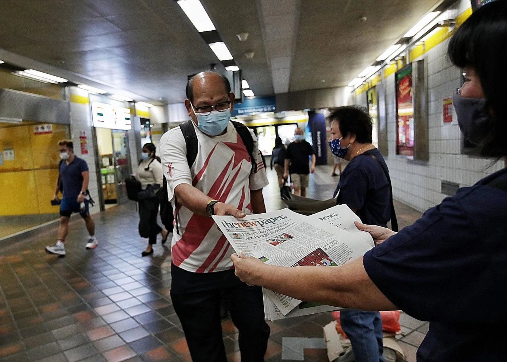 (Above) A commuter collecting The New Paper at Toa Payoh MRT station.