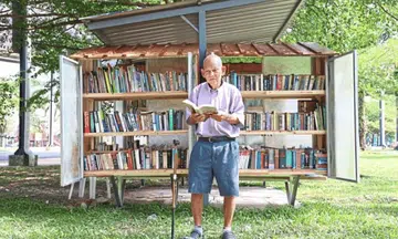 Elderly Malaysian man operates mini libraries in a park
