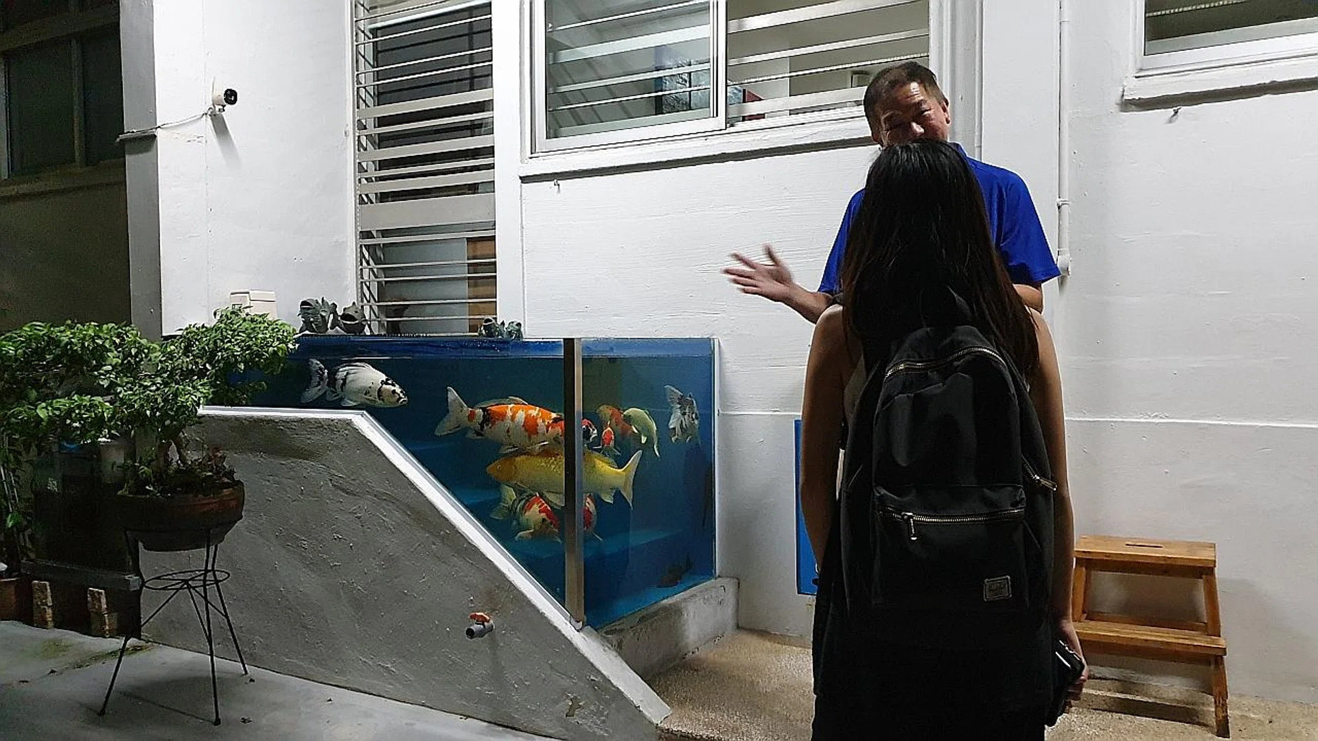 The owner (in blue) of the flat talking about his fish tank . 