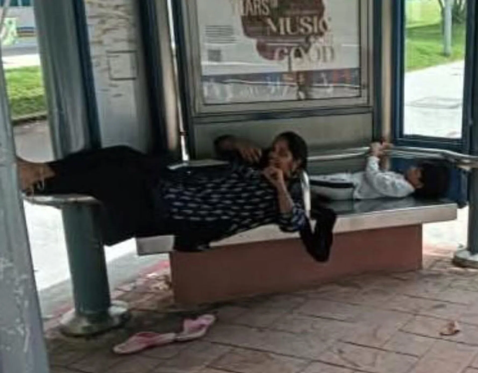 The woman was seen chatting on her phone while lying on the bus stop seat.