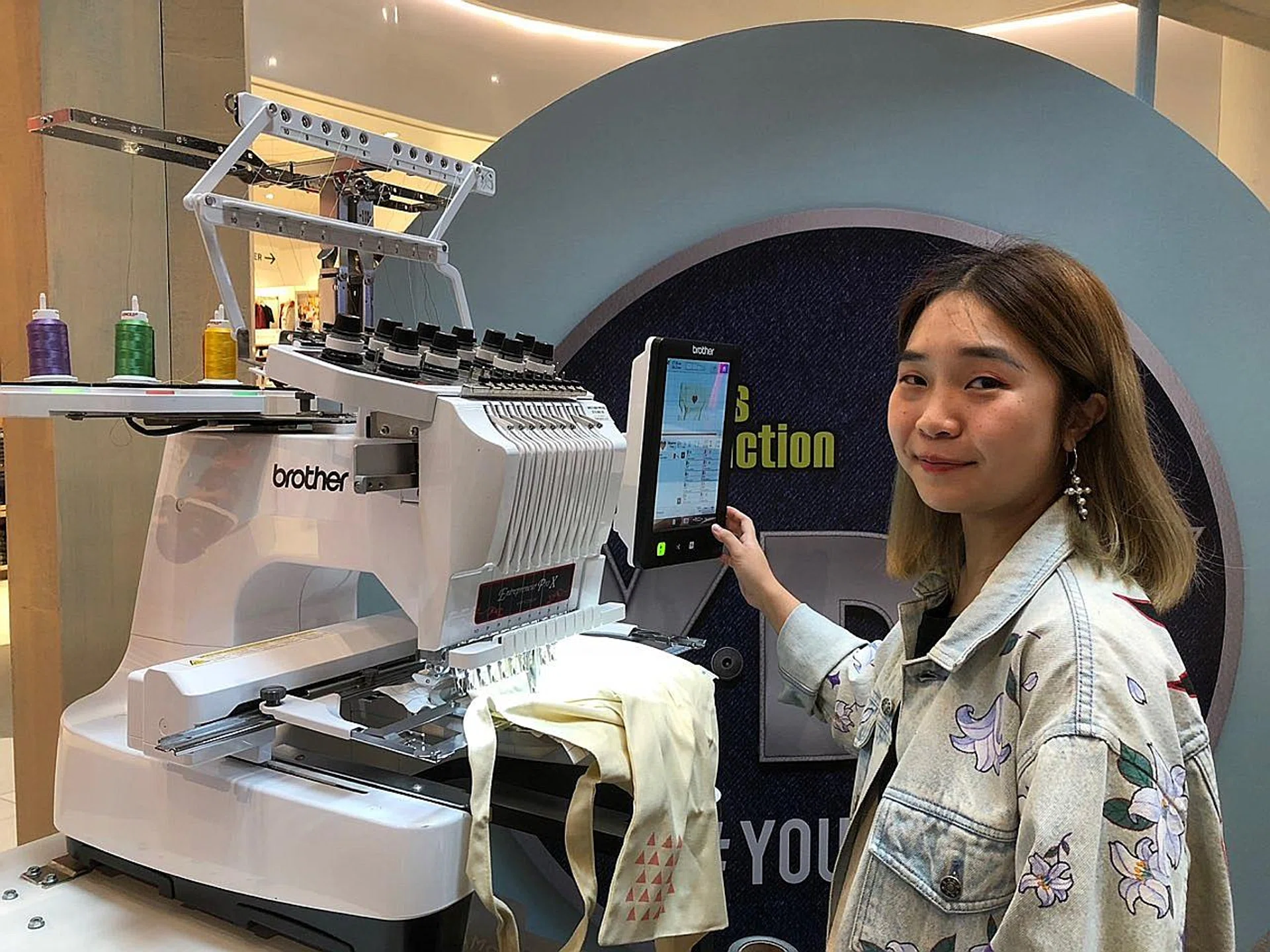 (Above) Playhood founder Sarah Lai using the embroidery machine to customise a tote bag. 