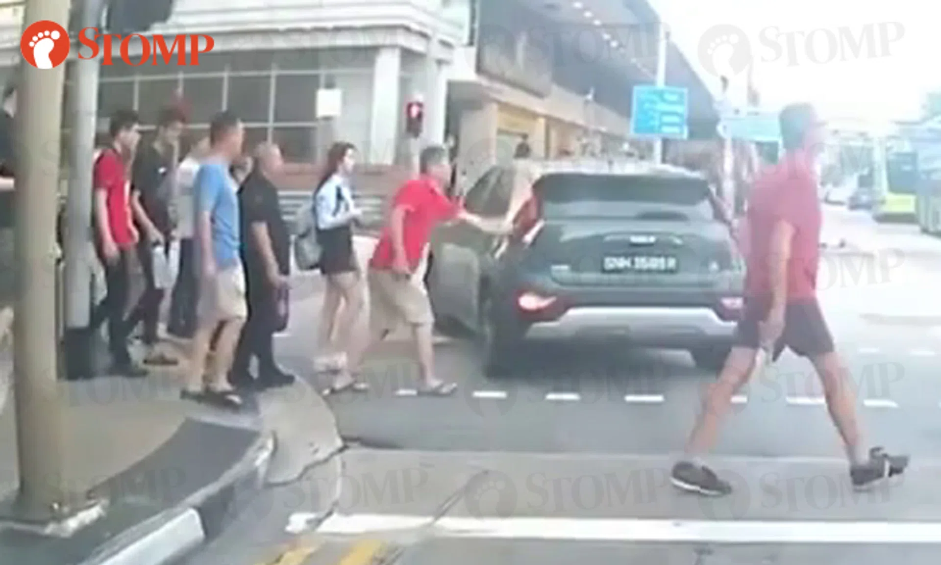 The man in a red shirt taps the car but the driver does not stop.