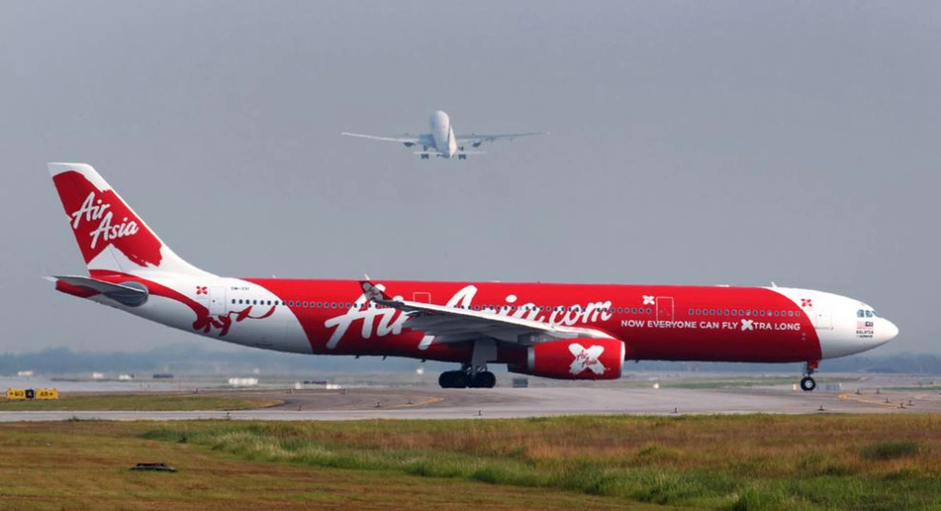 An aircraft operated by AirAsia X Bhd. taxis on the runway as another aircraft takes off at Kuala Lumpur International Airport in Sepang, Malaysia.
