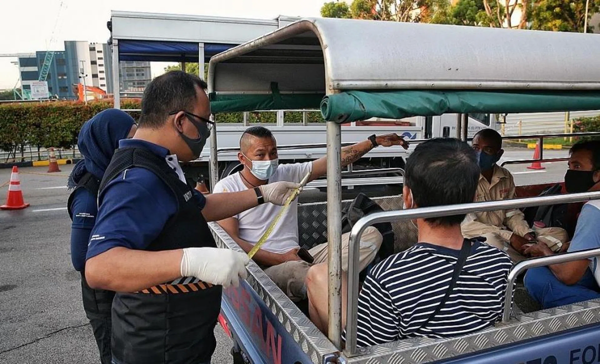 Ministry of Manpower inspectors using a measuring tape to check distances between workers to ensure compliance of safe distancing measures in the Jurong West and Tuas area yesterday. 