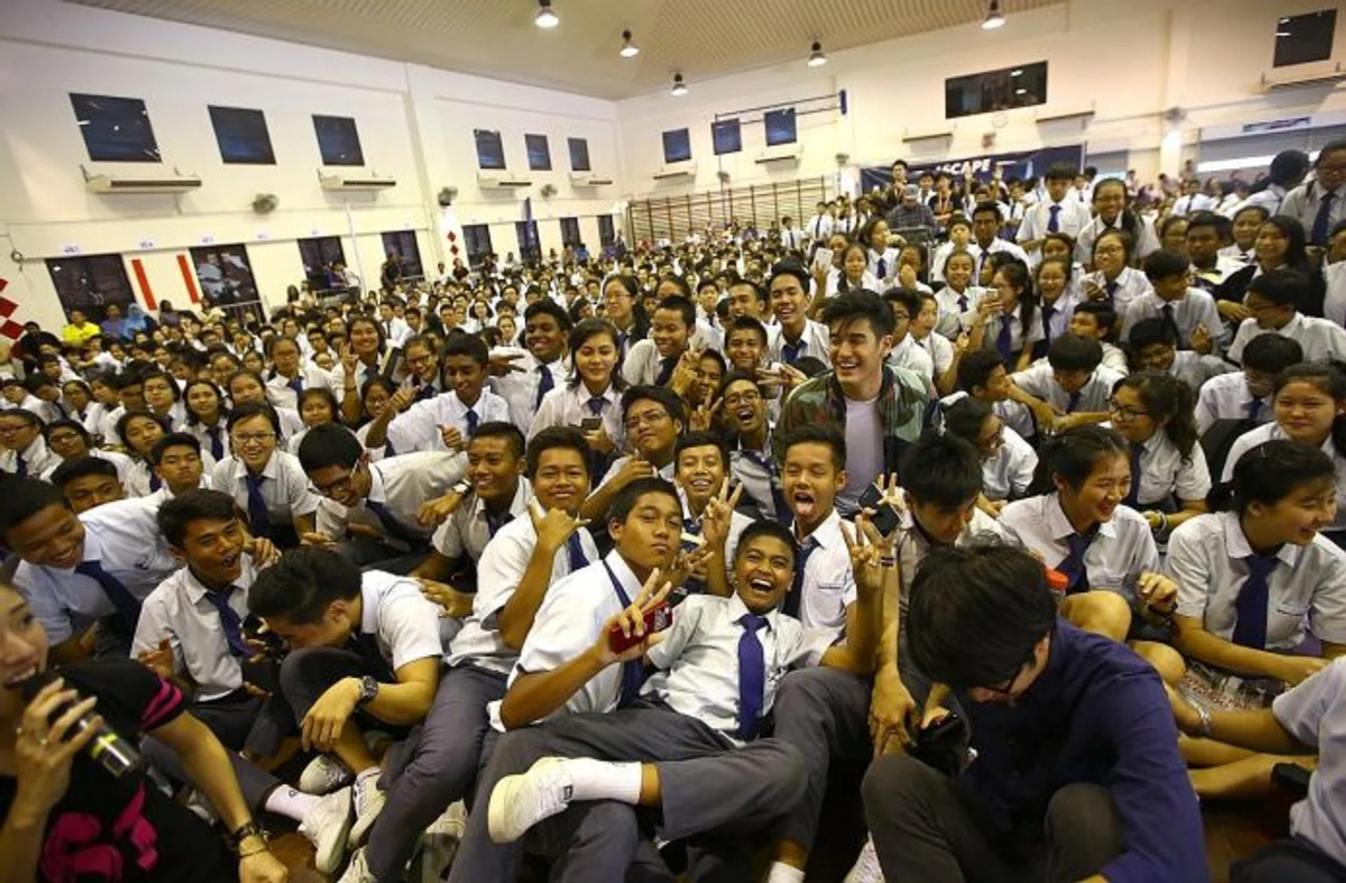 MUSIC IDOLS: Nathan Hartono and Charlie Lim posing with students at Canberra Secondary School (above) and performing for the crowd.