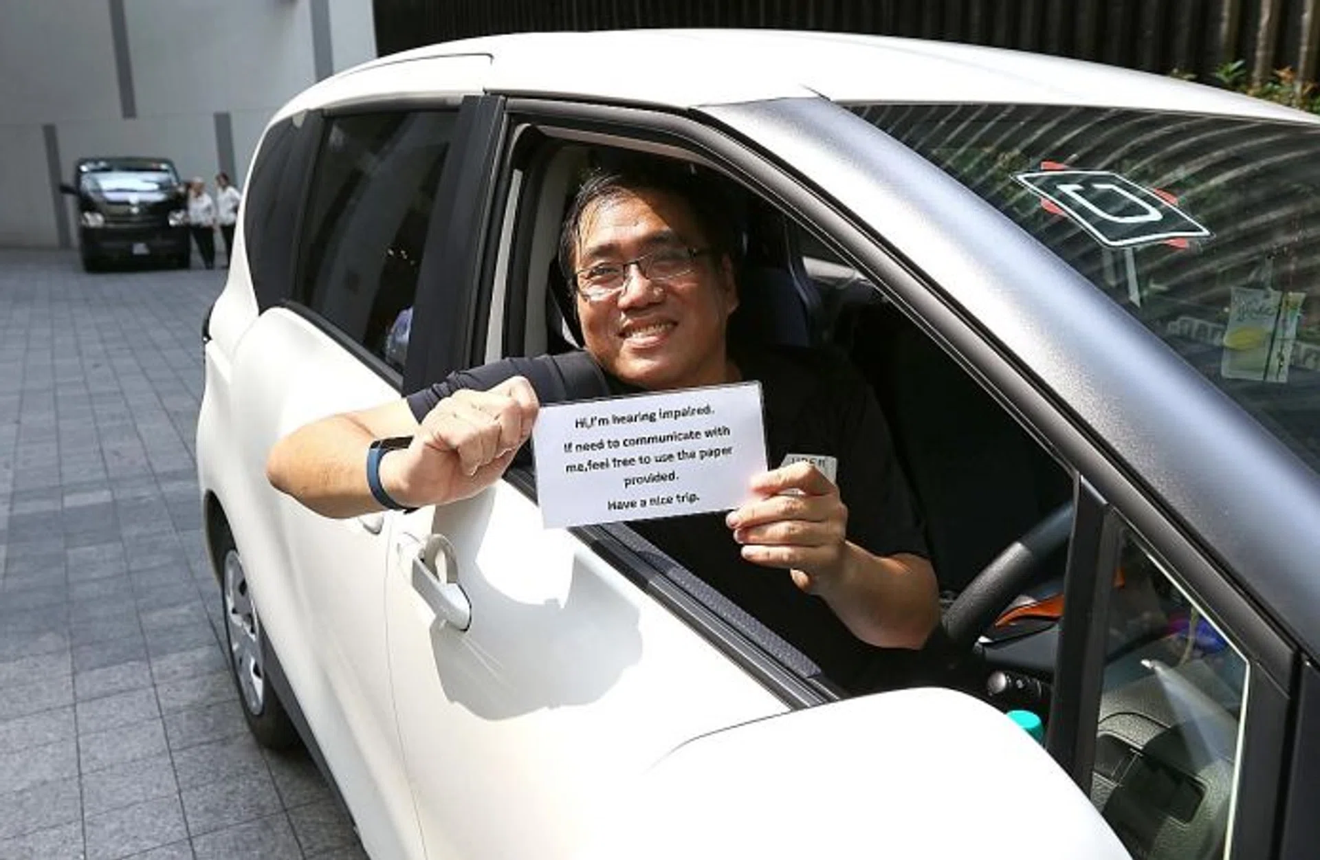 DEAF NOTE: UberX driver Roland Goh holding up a sign for his passengers that tells them he is hard of hearing. 