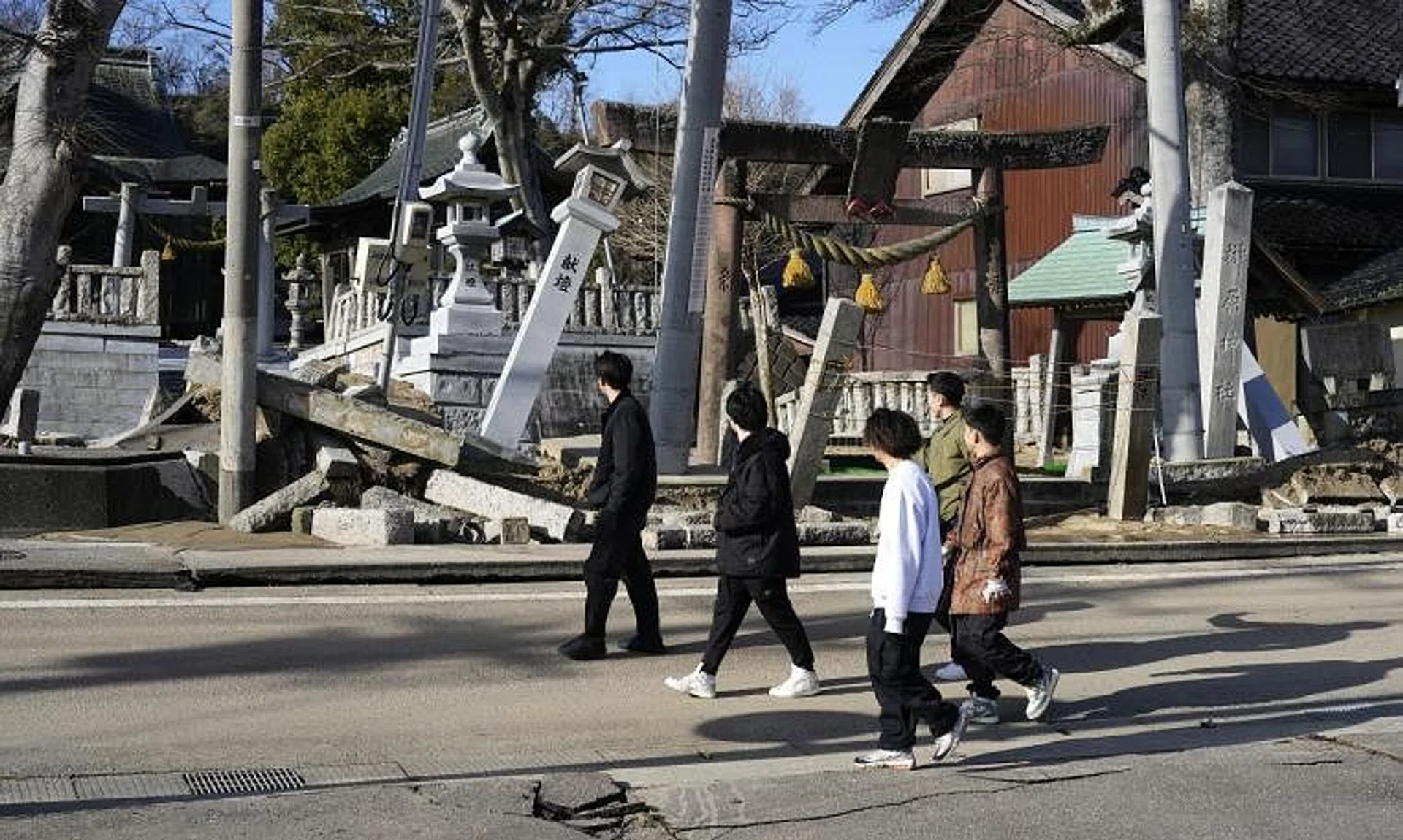 People walking past the collapsed Sakakibara shrine in Kohoku, Ishikawa Prefecture, on Jan 2, 2024.