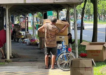 Couple sleep at Hougang bus stop, fearing their clutter along walkway would be stolen