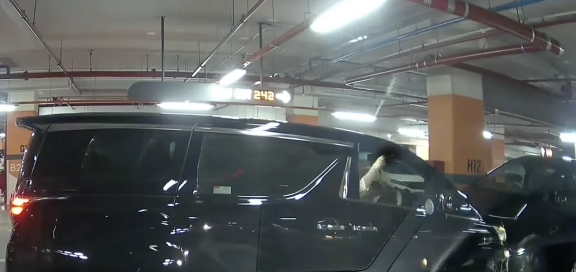 The woman flashes her middle finger as she struggles to park her car in the space.