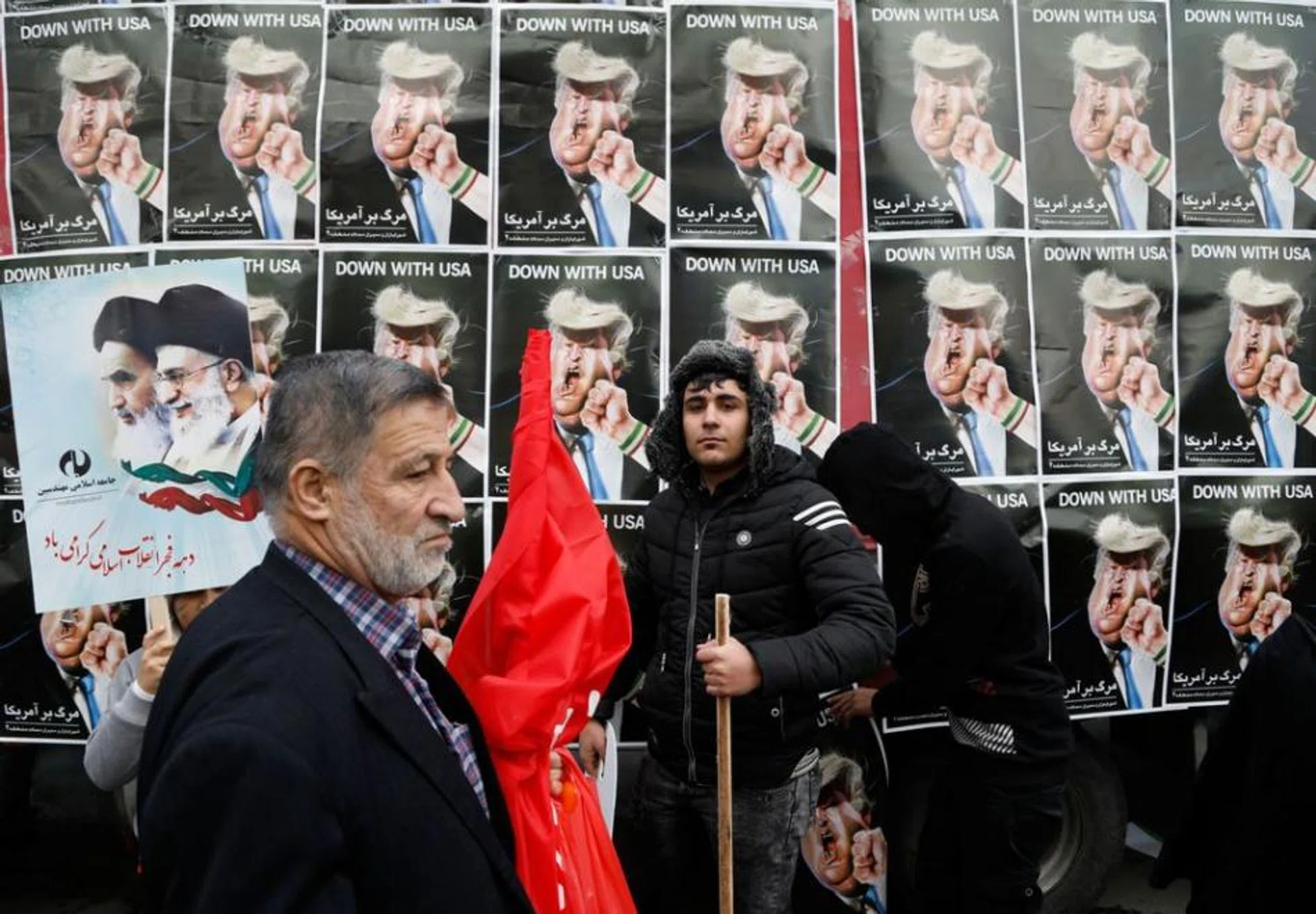 An Iranian man stands in front of placards showing a caricature of US President Donald Trump being punched by a hand wearing a bracelet of the Iranian flag during a rally marking the anniversary of the 1979 Islamic revolution on February 10, 2017, in the capital Tehran.