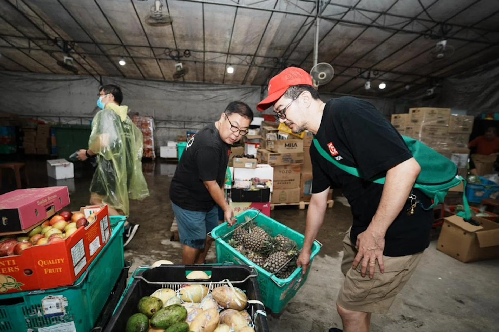 Food Rescue Sengkang co-founder Derek Ong (centre) saving a basket of pineapples from going to waste.