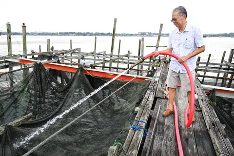 Mr Timothy Ng washing the nets of kelong E63, which he purchased in 2004.