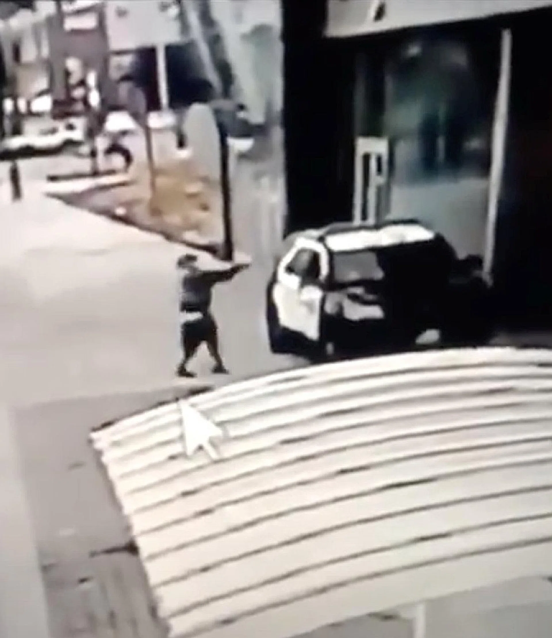 Footage shows the suspect approaching the parked vehicle on foot and firing with a handgun through the passenger side window before running away.  