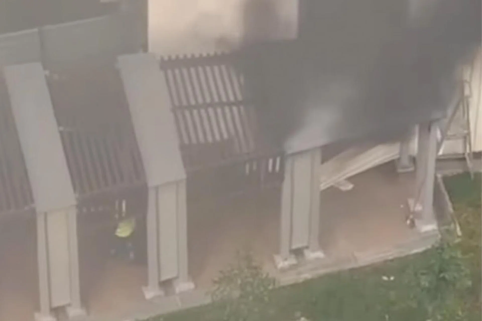 Thick black smoke billows from the ground floor of a Tampines HDB block as residents evacuate during the fire.