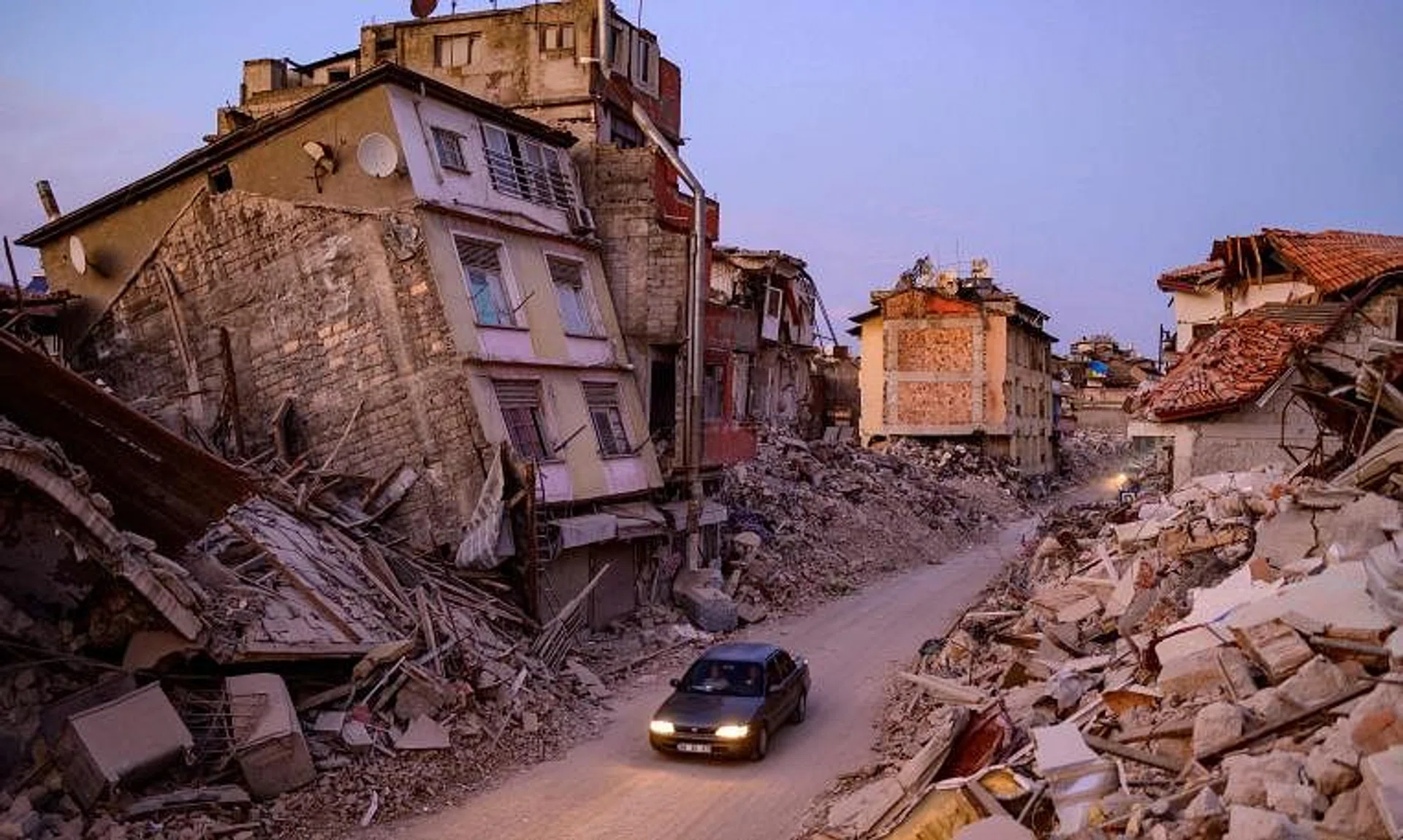 A car drives past collapsed buildings in Antakya, southern Turkey, on Feb 20, 2023.