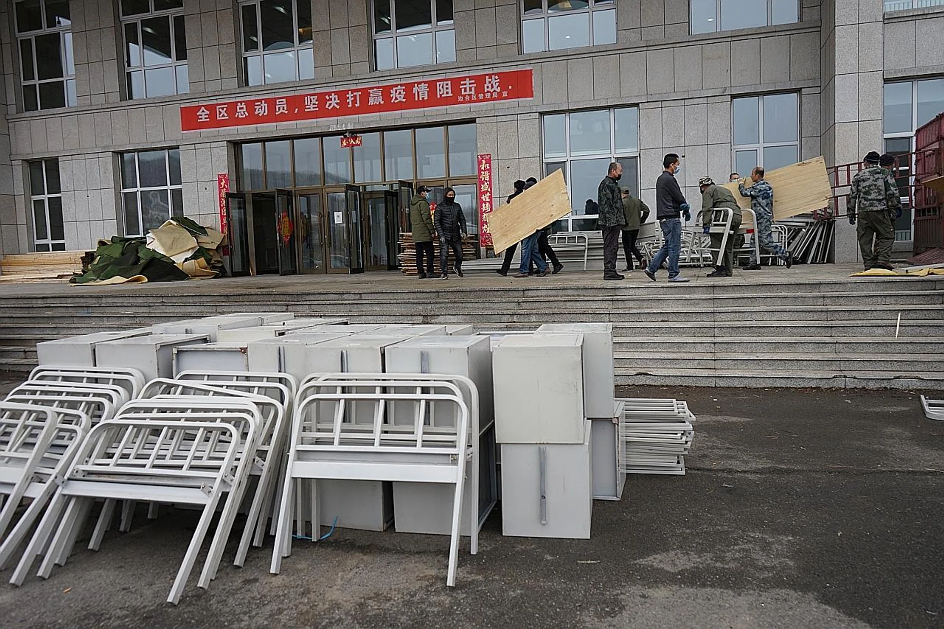 Workers moving bed parts into a makeshift hospital in Suifenhe, a Chinese border city that is bracing itself for more infections as natives return home from Russia. 