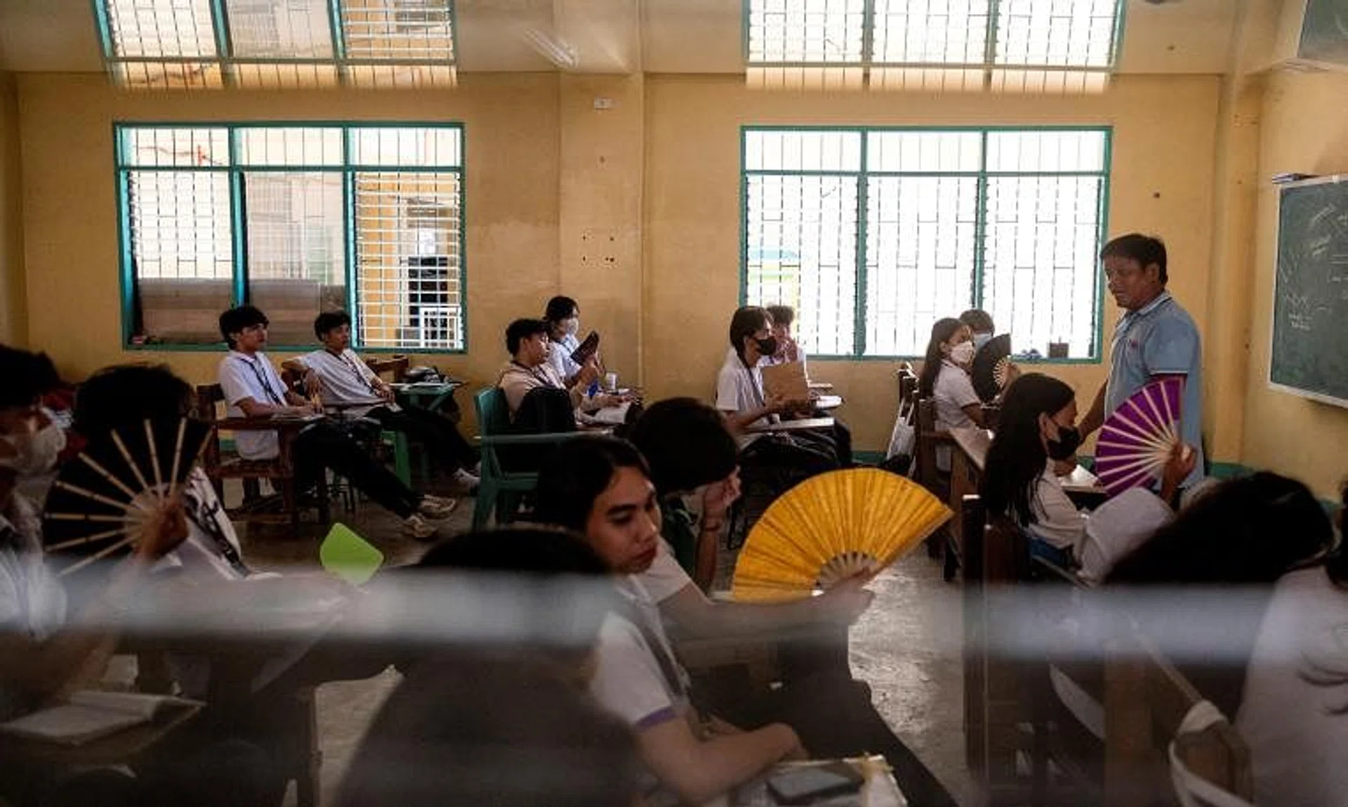 Grade 12 students use hand fans as they attend a class at the Commonwealth High School, in Quezon City, Metro Manila, on April 18.
