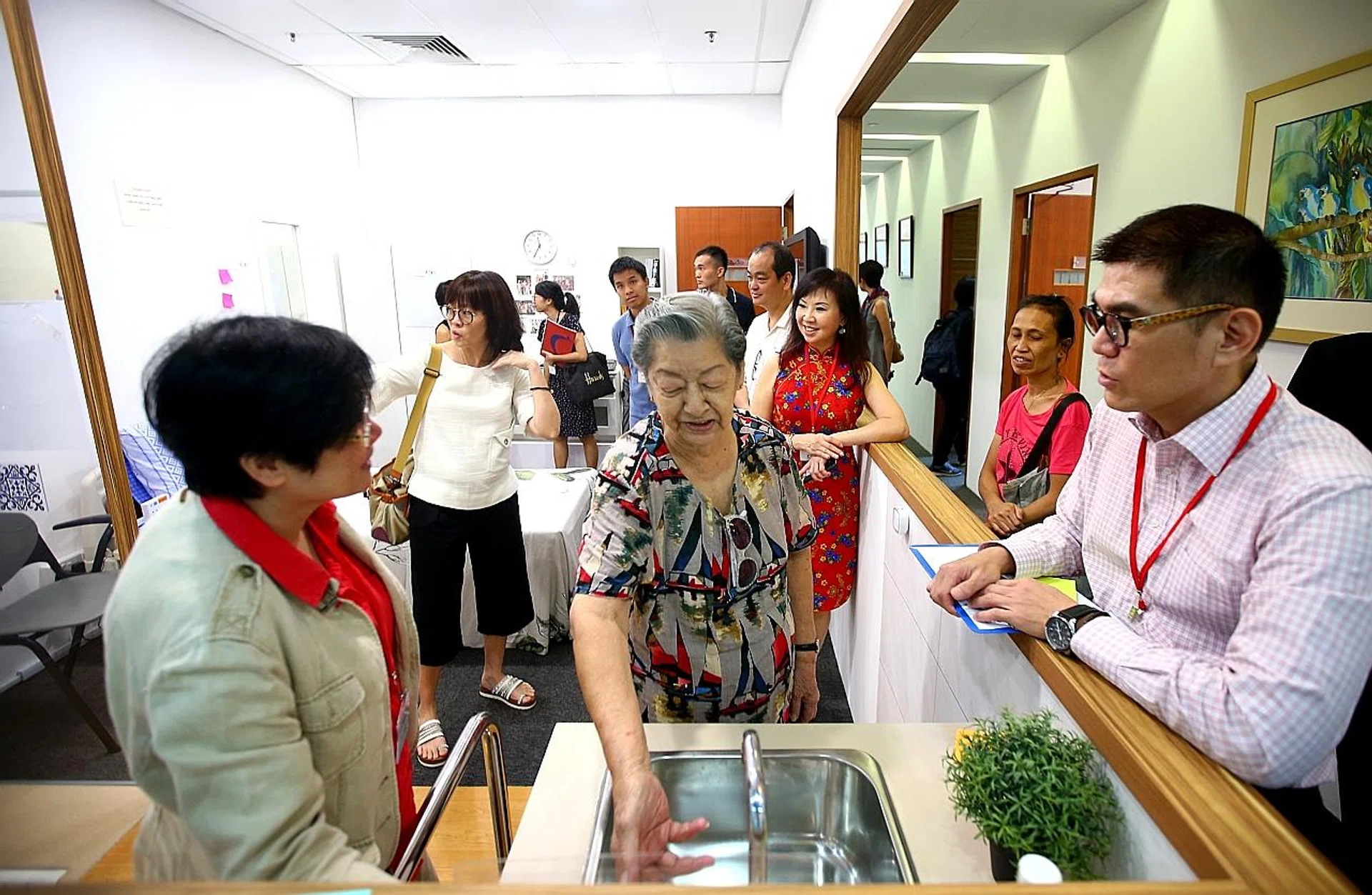CFS staff guiding a visitor, Madam Koh Seow Kim (centre), 86, through the mock-up studio apartment. 