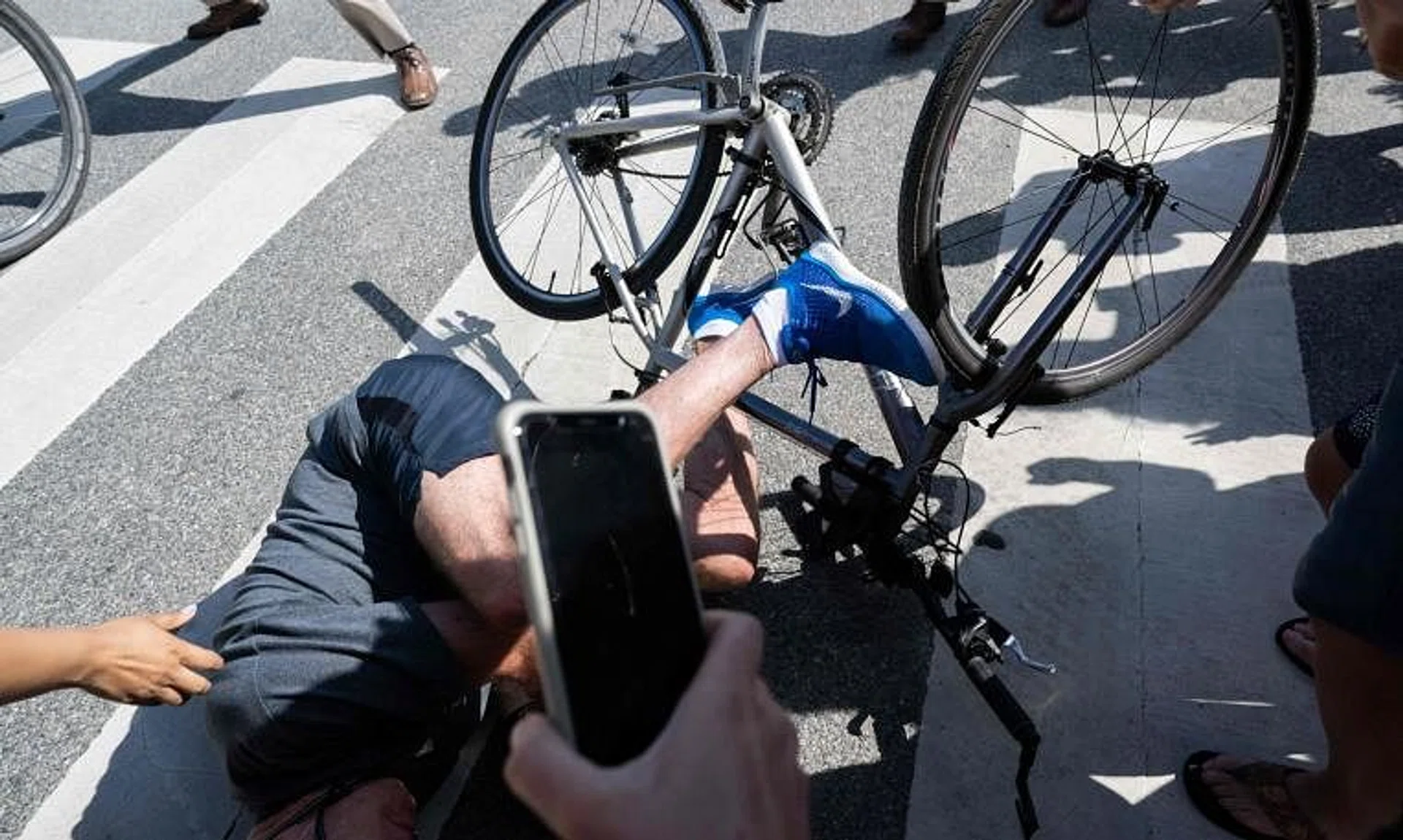 US President Joe Biden falls off his bicycle as he approaches well-wishers, following a ride at Gordon's Pond State Park in Rehoboth Beach, Delaware.