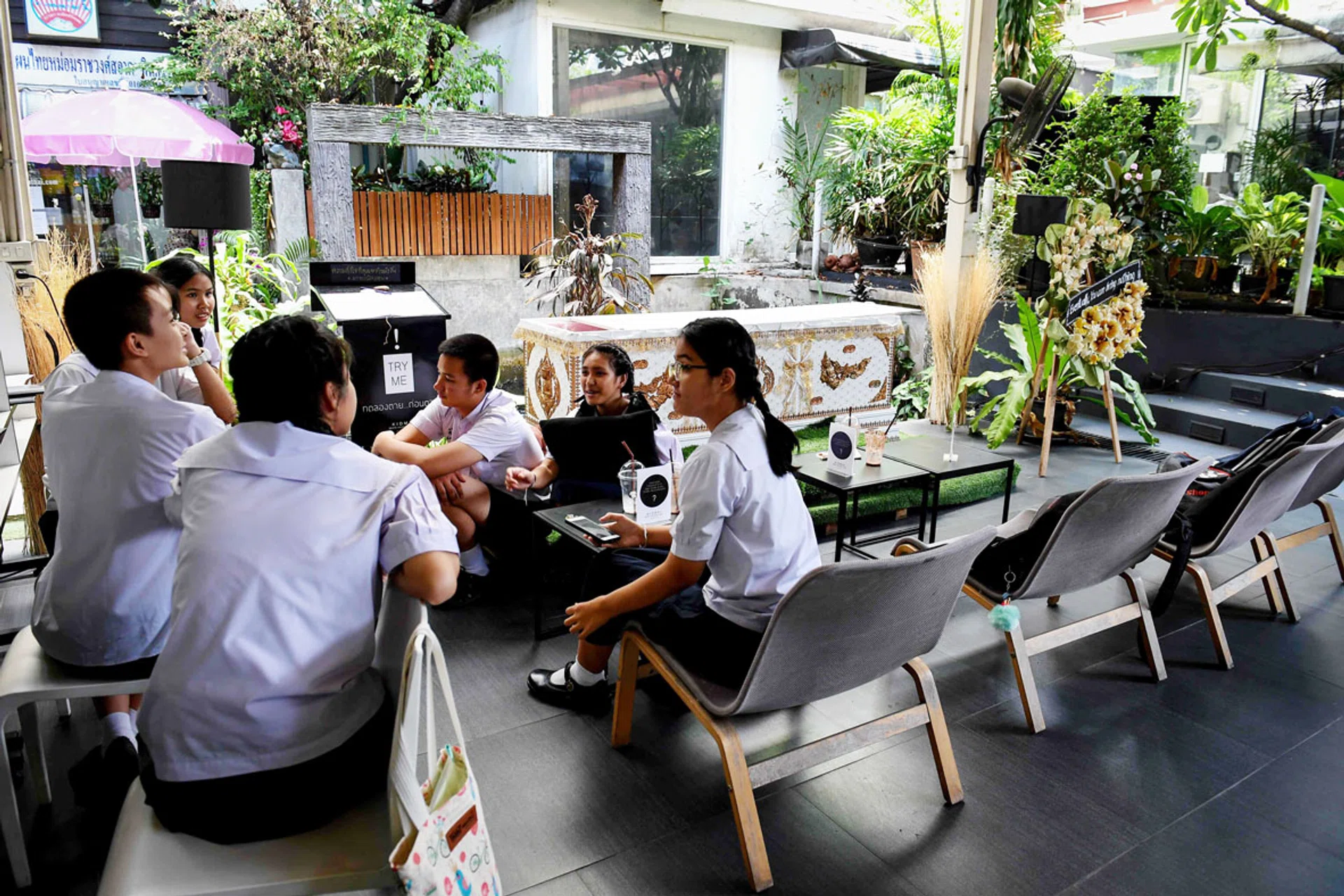 Teenagers lounging beside the coffin at the Kid Mai Death Awareness Cafe. 