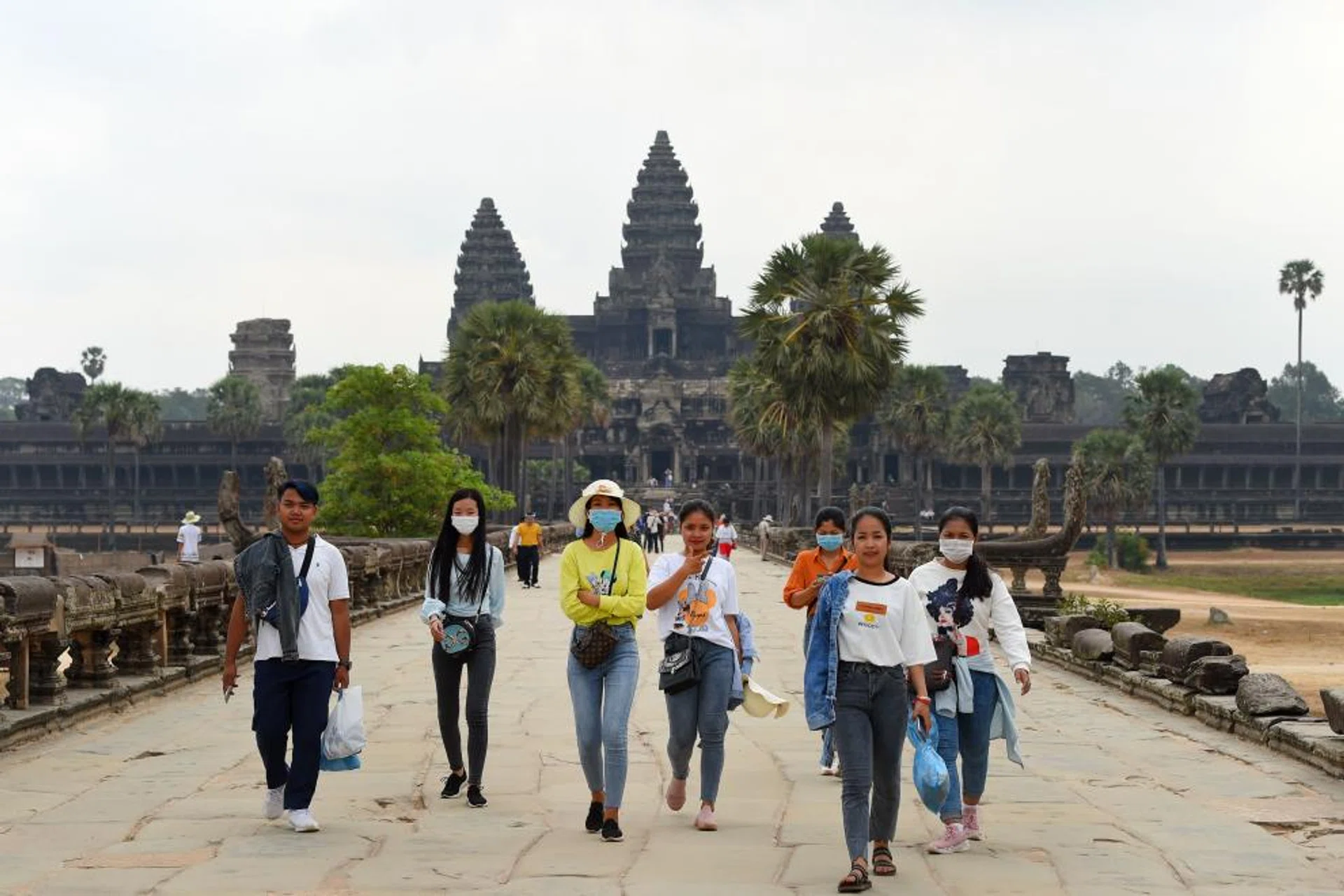 People wear facemasks, amid concerns about the spread of the COVID-19 novel coronavirus, as they visit the Angkor Wat temple in Siem Reap province on March 6, 2020. - The deadly COVID-19 novel coronavirus epidemic will cost world tourism at least $22 billion owing to a drop in spending by Chinese tourists, the head of the World Travel and Tourism Council said on February 27.