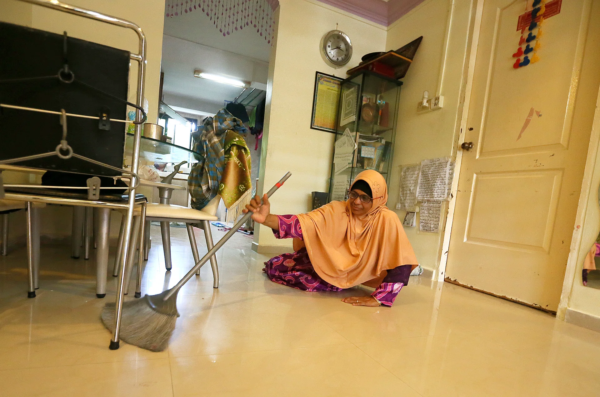 RESILIENT: Madam Fatimah Bivee, 53, crawling in her flat to sweep it every day.