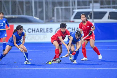 Singapore hockey player Ivy Chan challenging for the ball against Chinese Taipei with teammate Valerie Tay looking on.