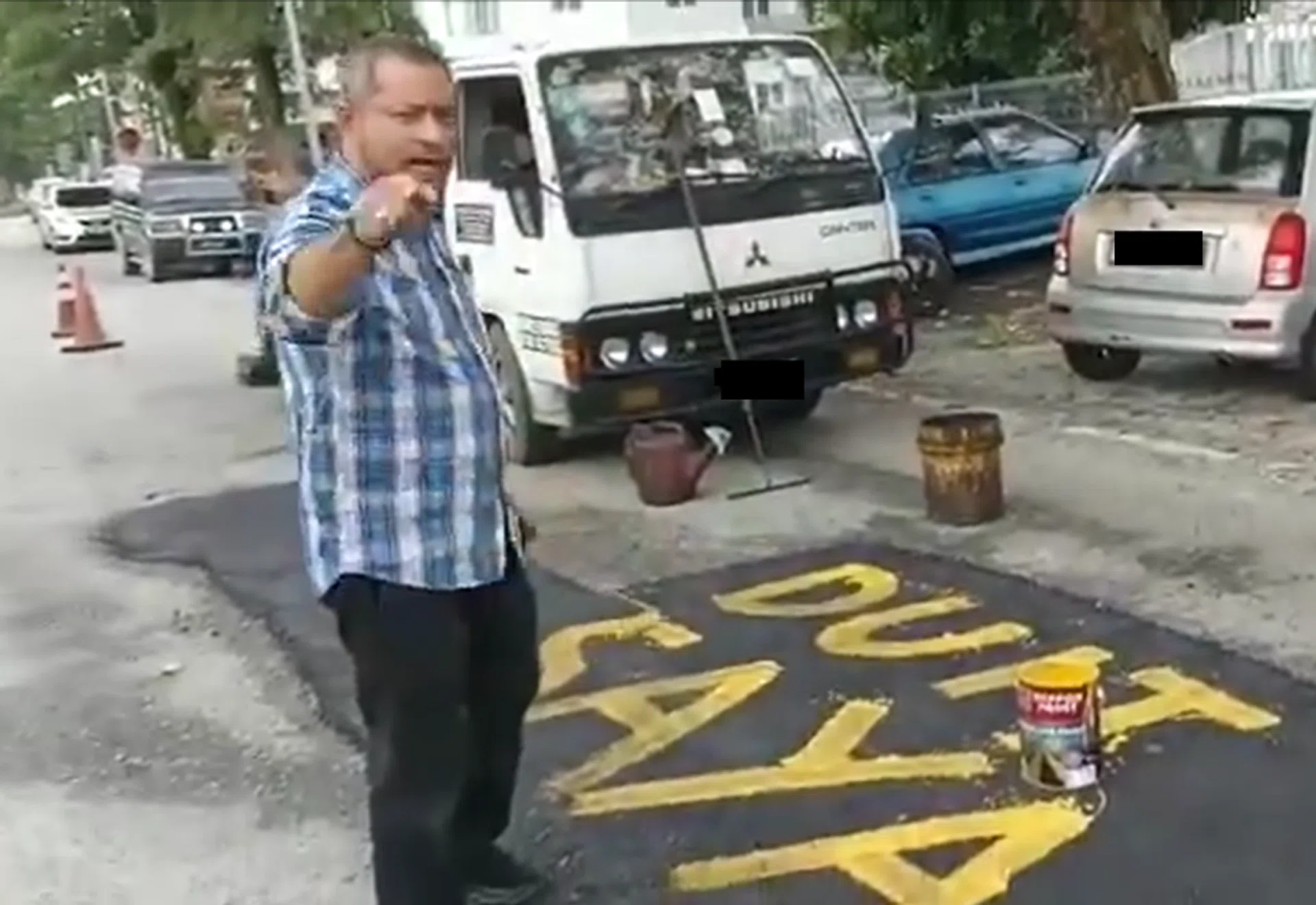 The man wrote "DUIT SAYA" (Malay for my money) after fixing the pothole.