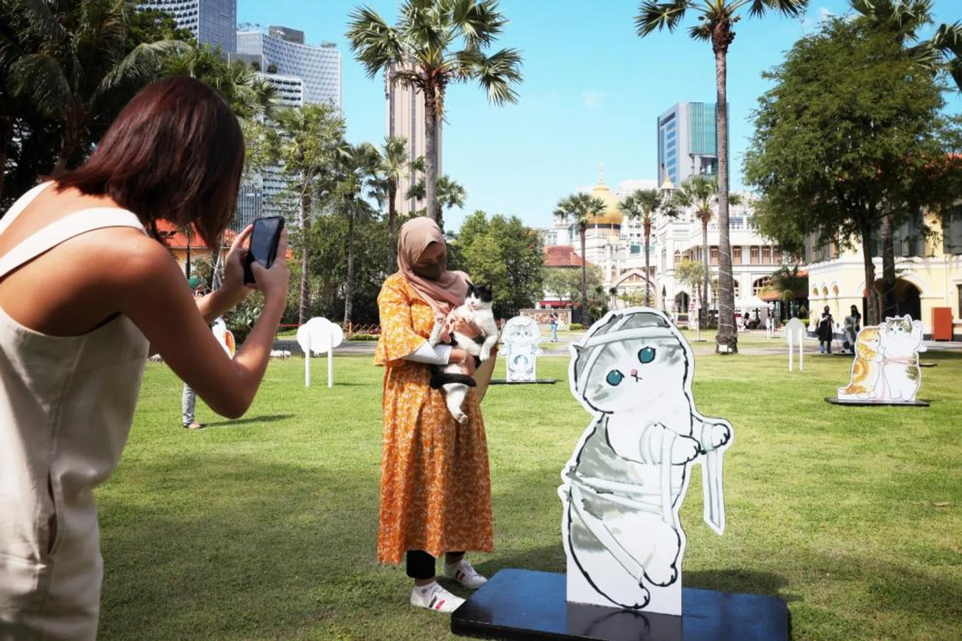 One of the resident cats sniffing out the cat standees on the lawn of the Malay Heritage Centre. 