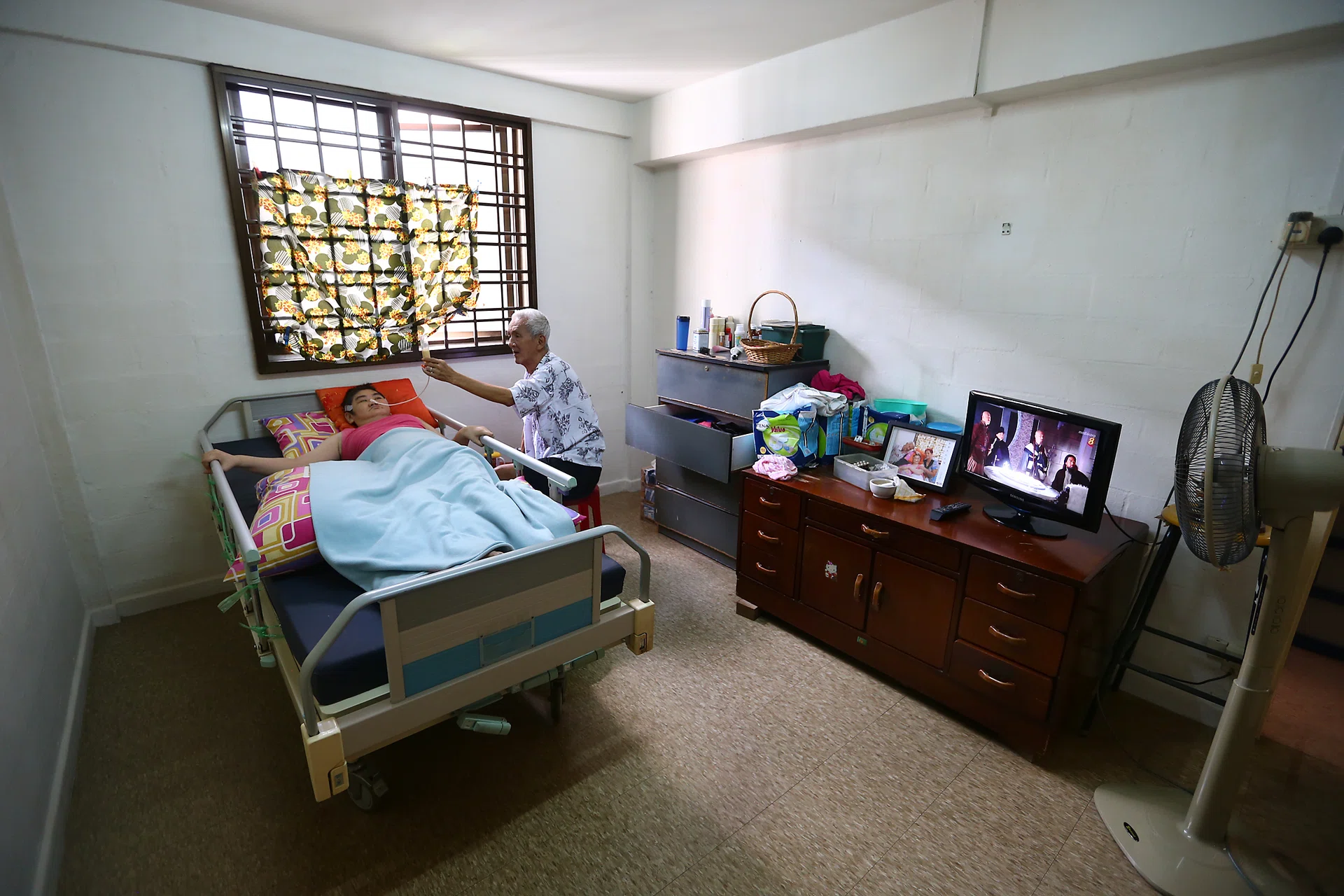 DEVOTED: Mr Ng Moh Hiong, 72, and his wife, Madam Lau Siew Lan, 69, take turns watching over their bedridden, 38-year-old daughter, Margaret.