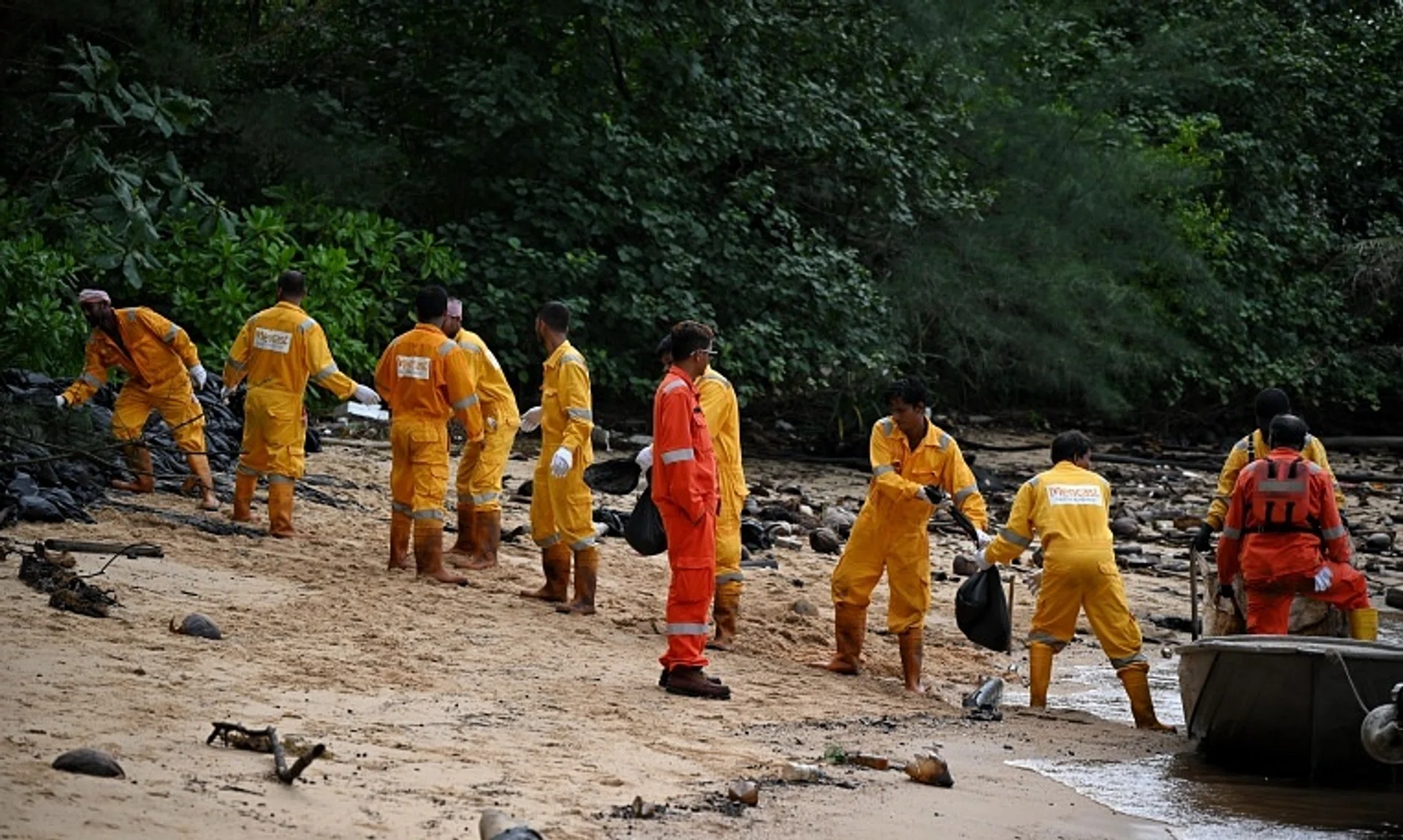 When the tide comes in at East Park, the workers form a human chain to load the boat with bags of oil-stained sand, which brings it back to a staging area. 