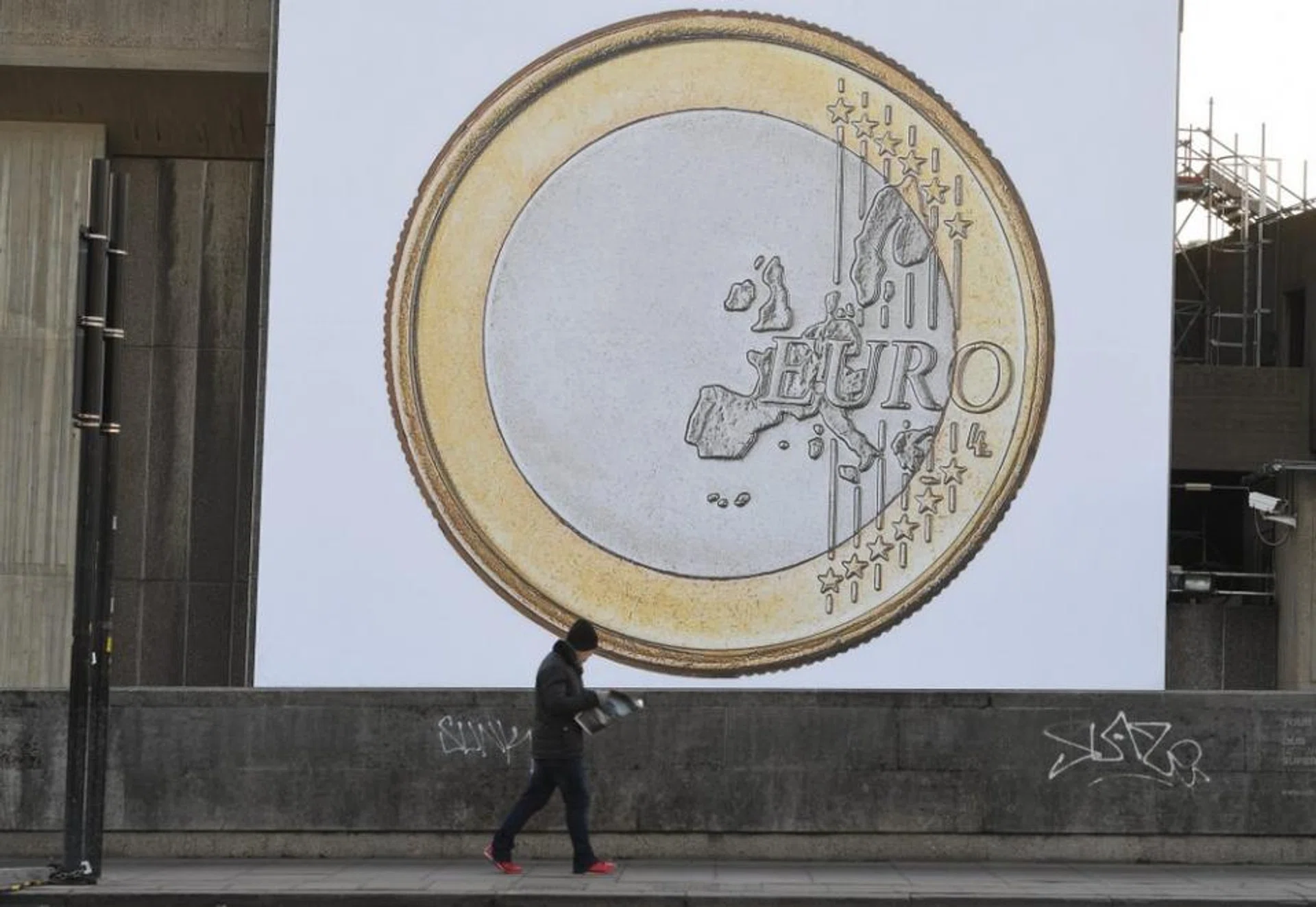Pedestrians walks past by a giant poster of a Euro coin near Waterloo in London, Britain, 24 January 2017.
