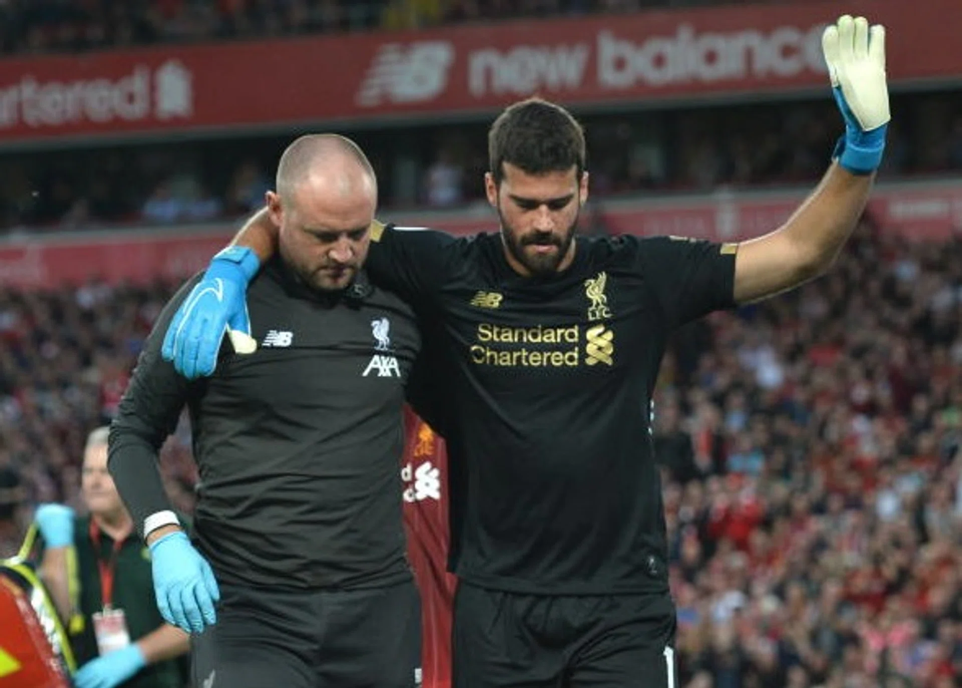 Liverpool goalkeeper Alisson (right) receiving medical treatment for a calf injury.